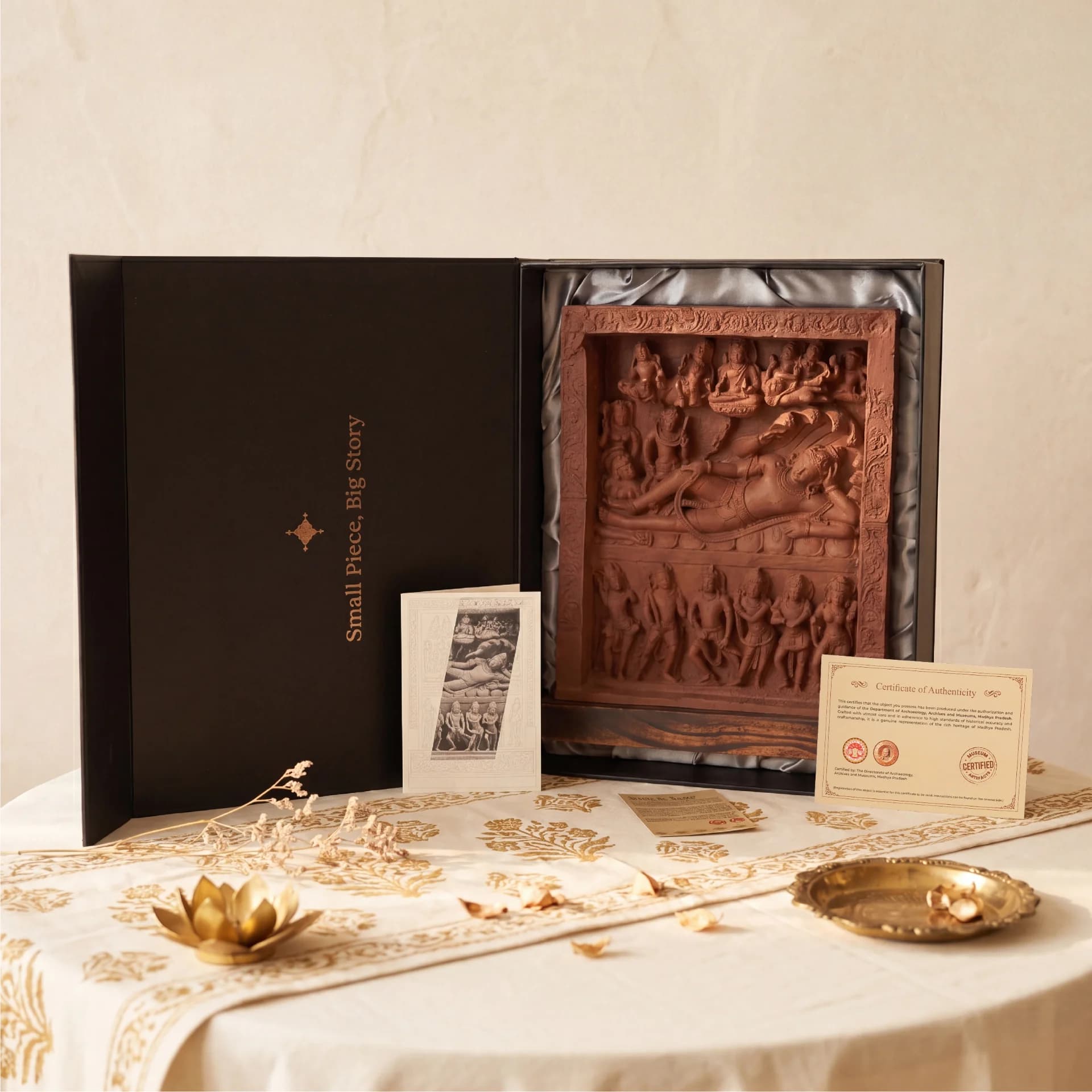 An Anantasayana Vishnu Sculpture museum replica displayed in a black presentation box with its certificate of authenticity on a table.