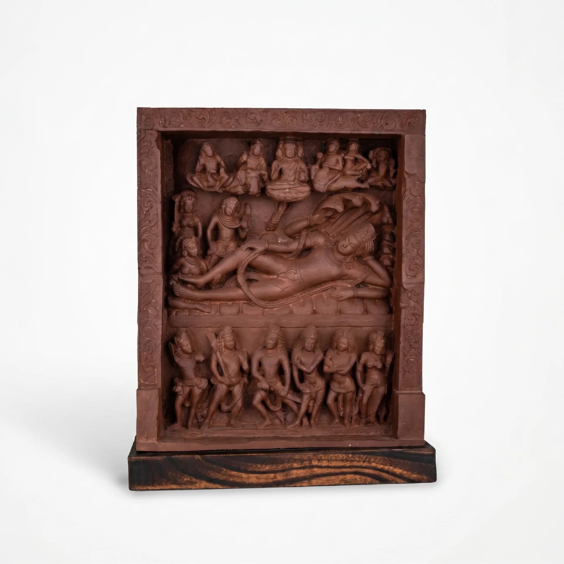 A front-facing view of the Anantasayana Vishnu Sculpture, featuring intricate terracotta-style carvings of deities on a dark wooden base.