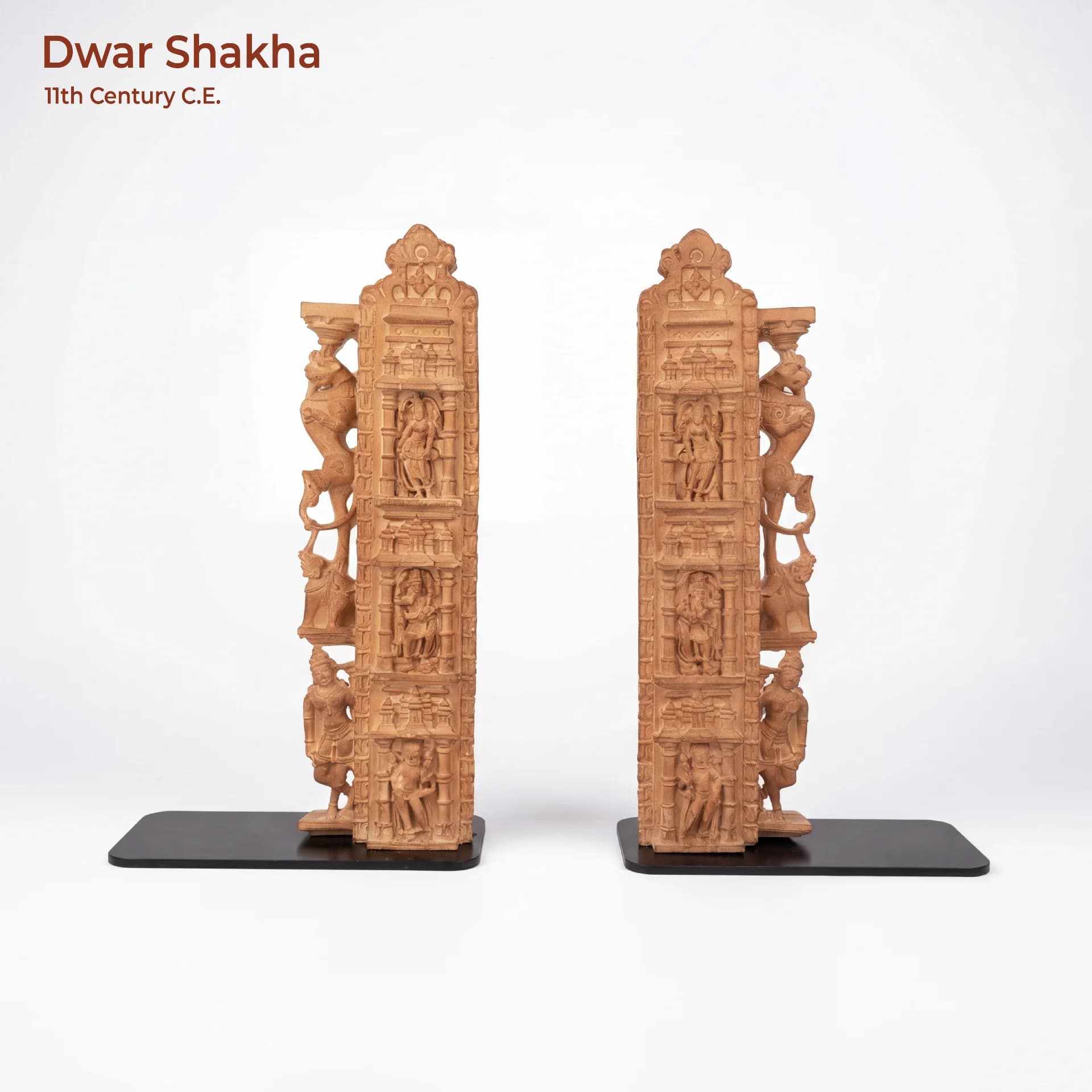 A pair of Dwar Shakha Sculpture bookends featuring intricate stone composite carvings of celestial figures on black bases.