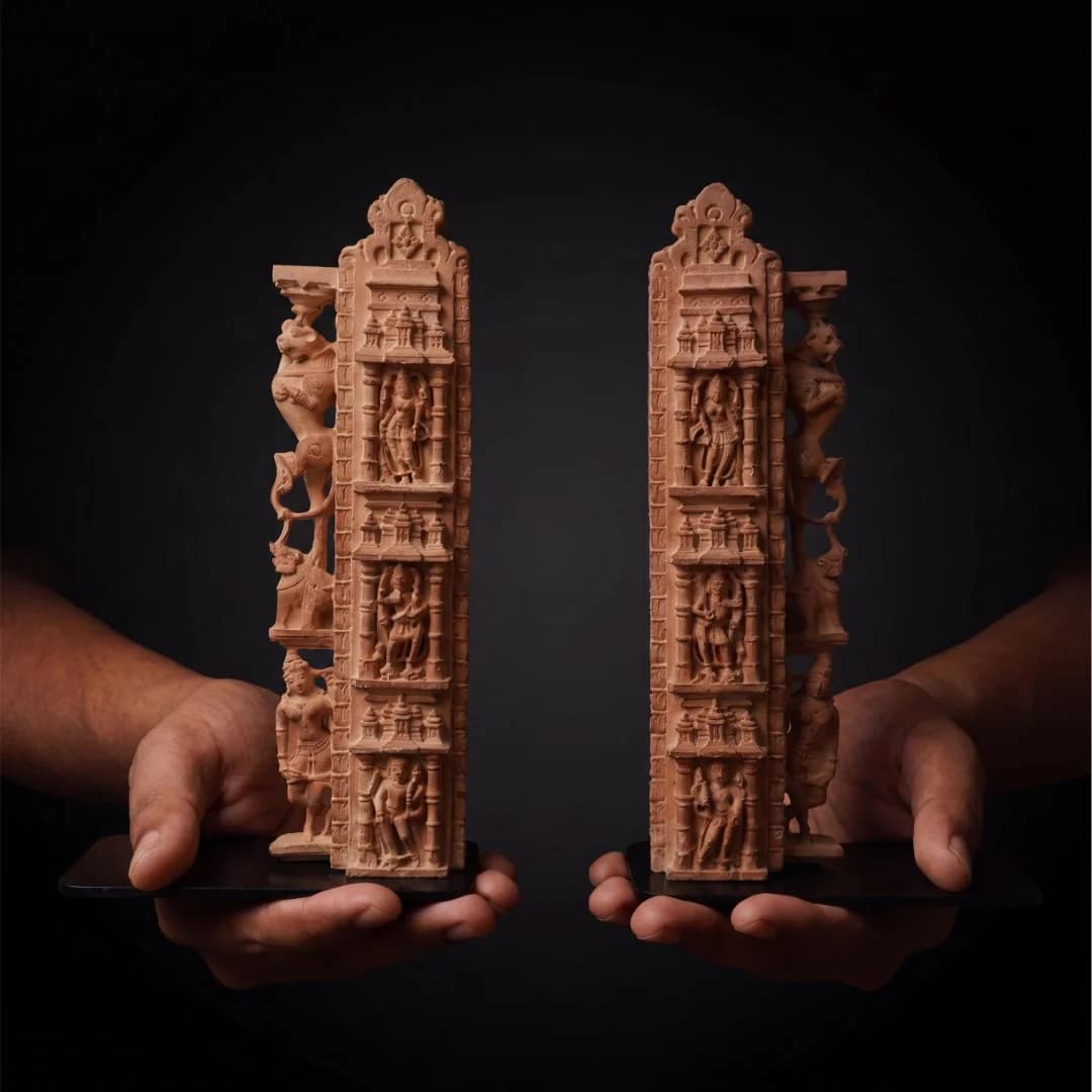 Two hands hold a pair of Dwara Shakha Sculpture stone composite bookends featuring intricate 11th-century temple architectural carvings.