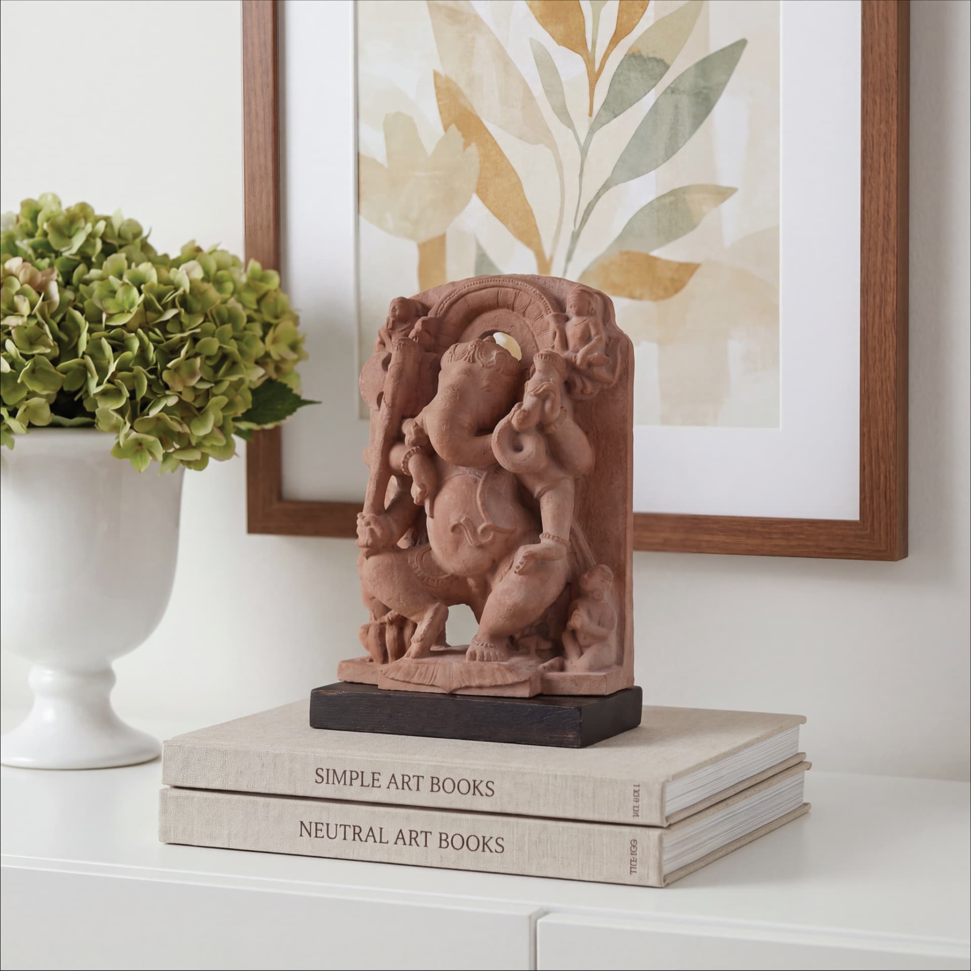 A Ganesha Sculpture replica displayed on stacked books, featuring a handcrafted terracotta-style finish in a modern home decor setting.