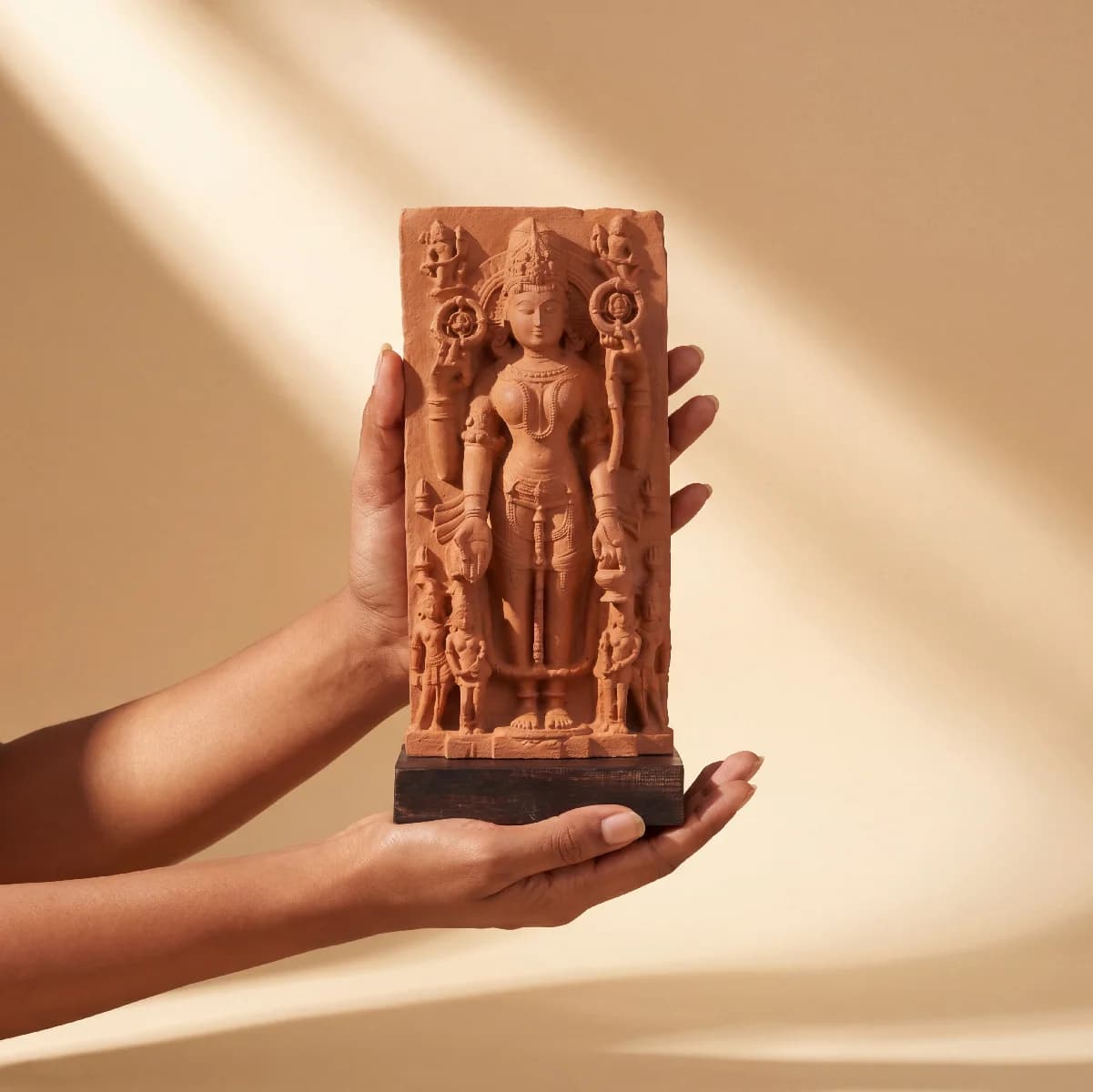 A pair of hands holding the Gauri Parvati Sculpture, a detailed stone composite replica of a 10th-century Hindu temple artifact.