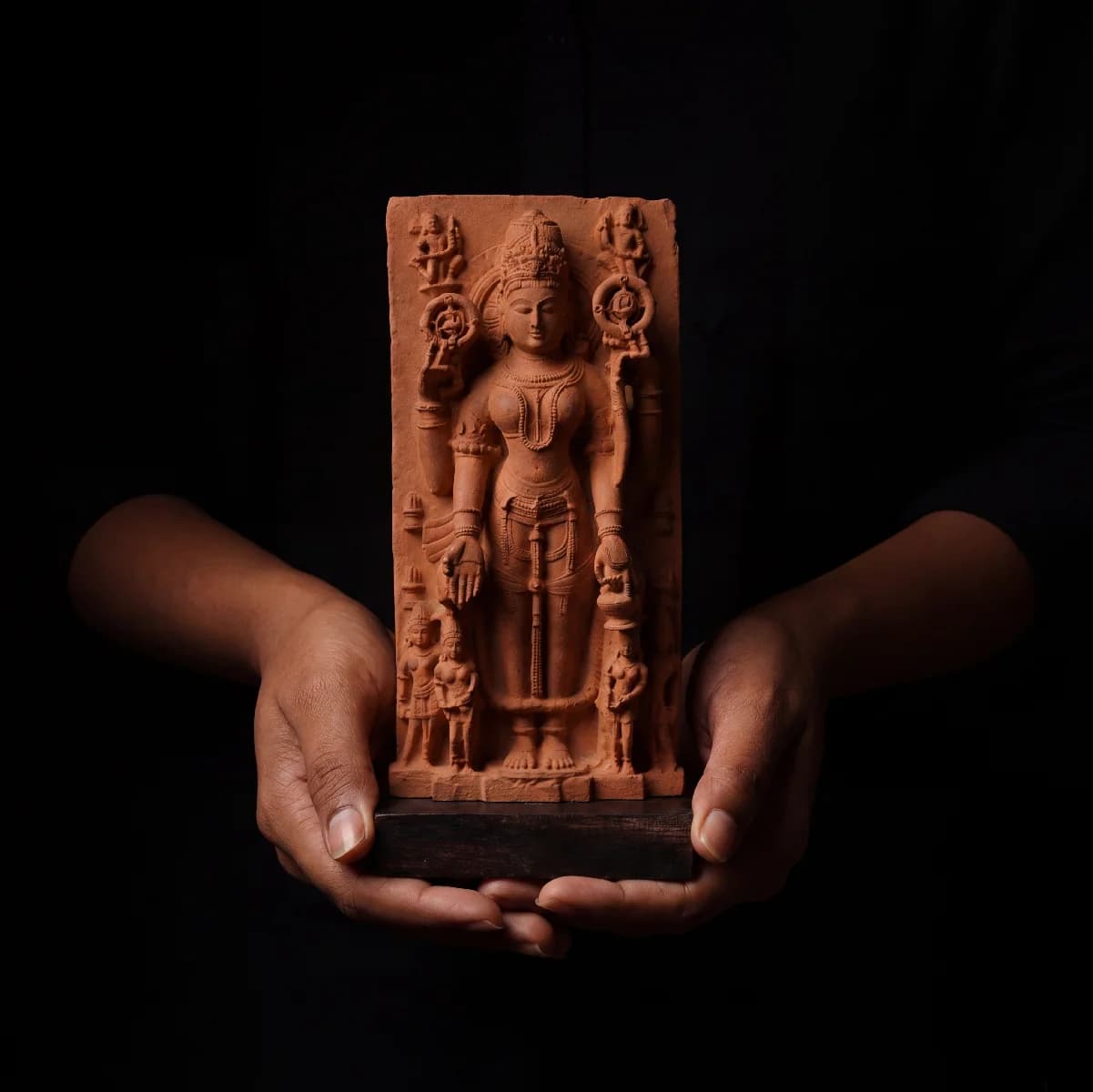 A pair of hands holds a Gauri Parvati Sculpture, a detailed stone composite replica of a 10th-century Hindu temple artifact.