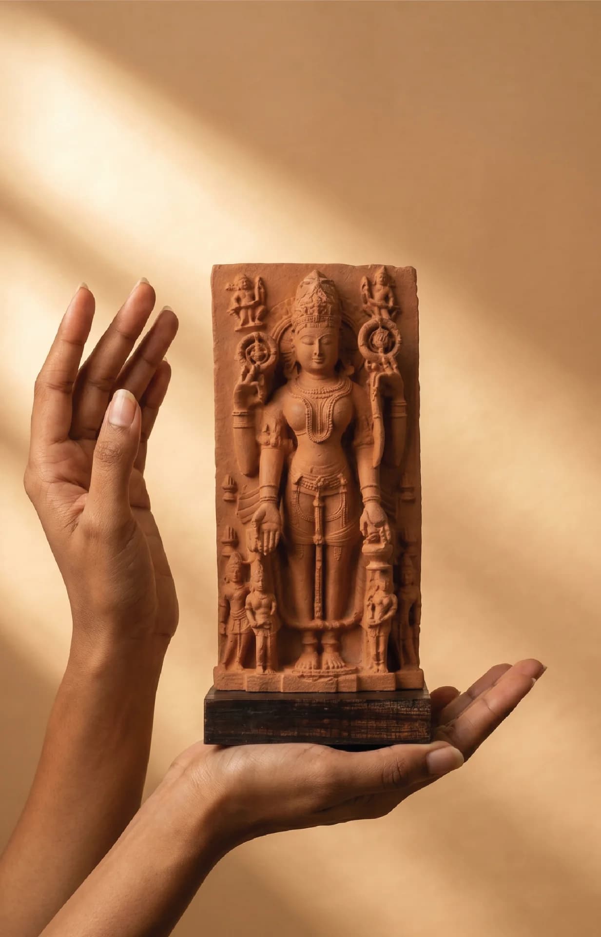 A pair of hands cradles the Gauri Parvati Sculpture, a detailed stone composite replica of a 10th-century Pratihara temple artifact.