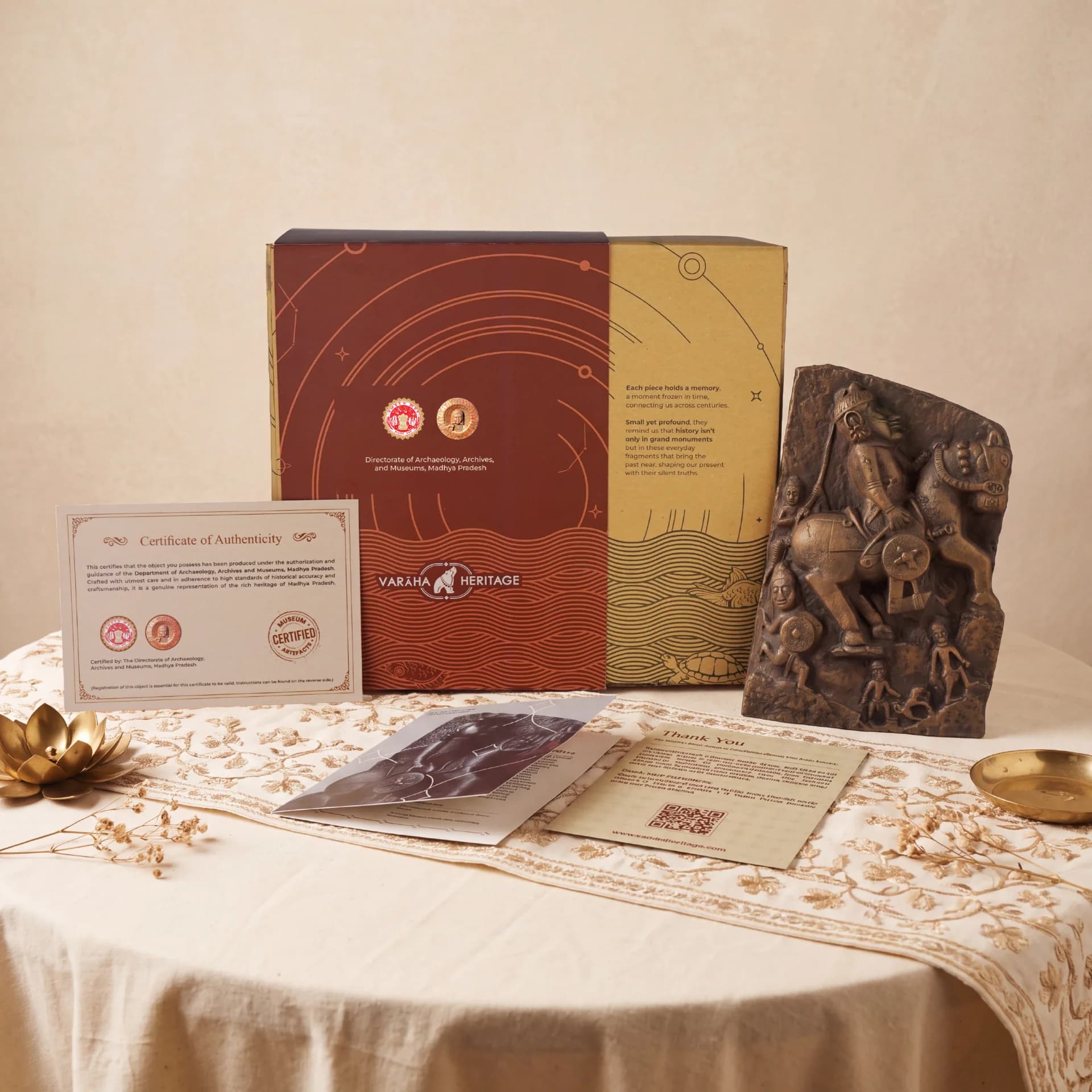 The Goud Yoddha stone sculpture replica displayed alongside its branded packaging, certificate of authenticity, and informational cards on a table.