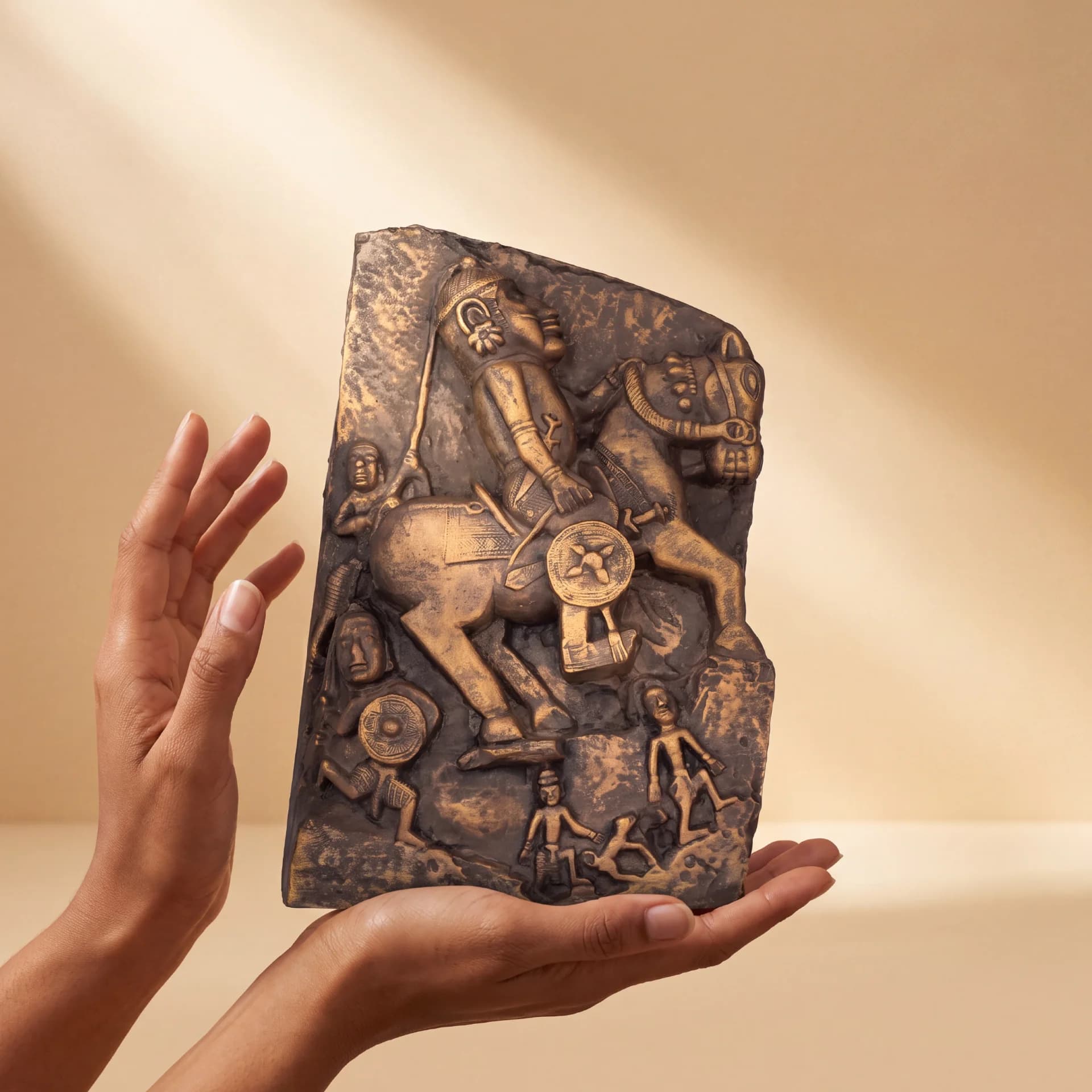 A pair of hands cradles a Goud Yoddha stone relief featuring an intricate 17th-century style horseman sculpture.