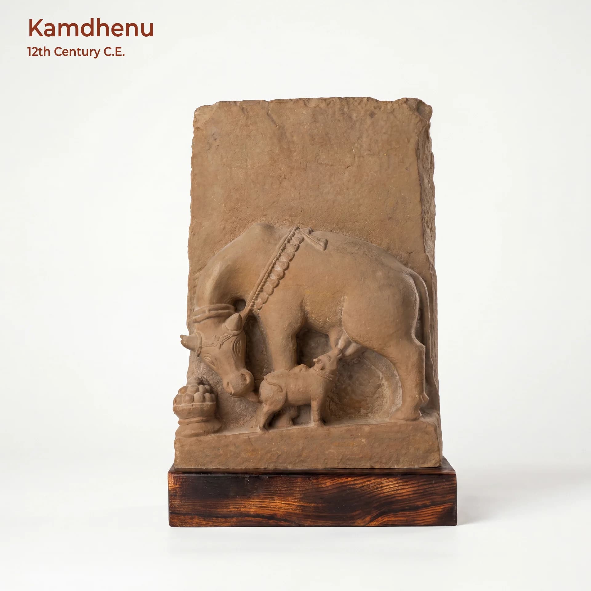 A front-facing view of the Kamdhenu Sculpture, a stone composite museum replica depicting a divine cow nursing her calf.