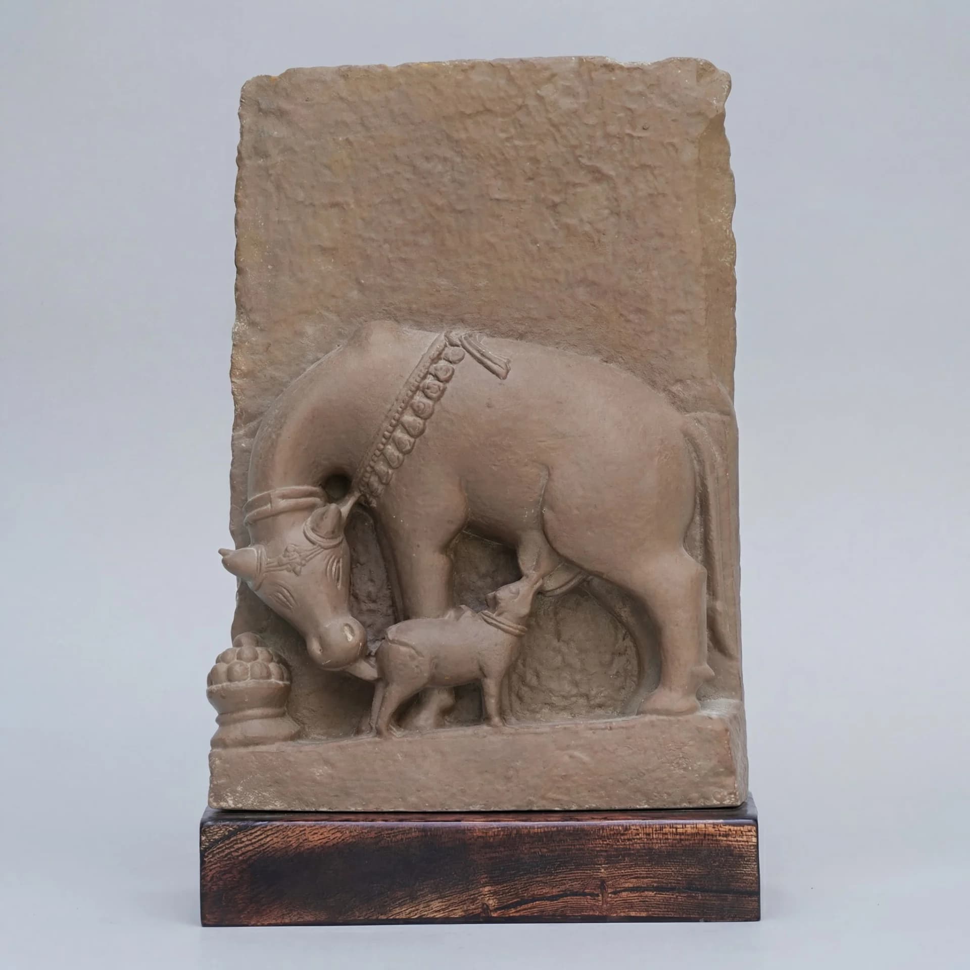 A front view of the Kamdhenu Sculpture, a stone composite relief depicting a cow nursing its calf with traditional ornamentation.