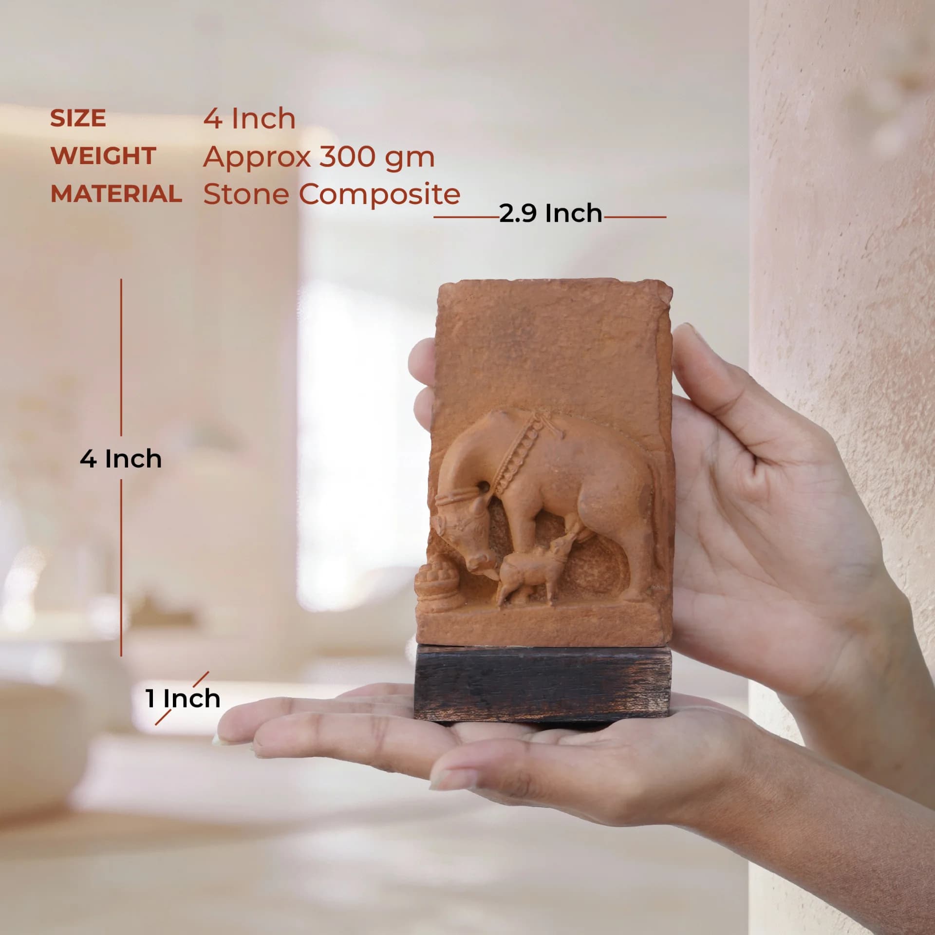 A pair of hands holding a stone composite Kamdhenu Sculpture, showing its scale with overlaid text indicating dimensions and weight.