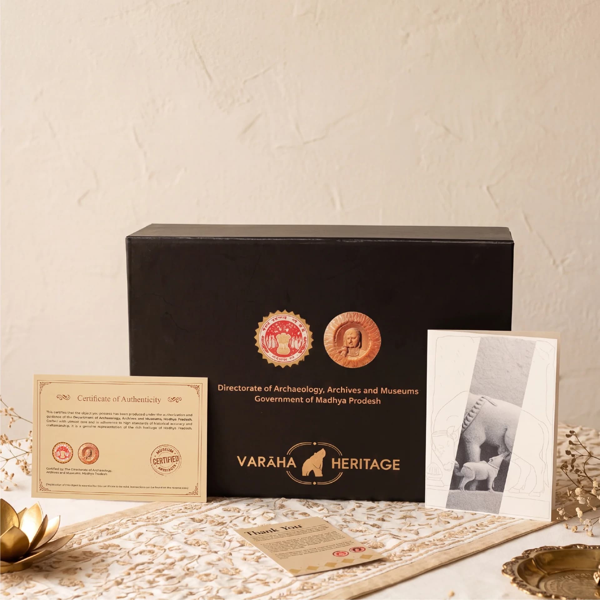 The Kamdhenu Sculpture packaging box displayed with its official certificate of authenticity and a decorative heritage information card.