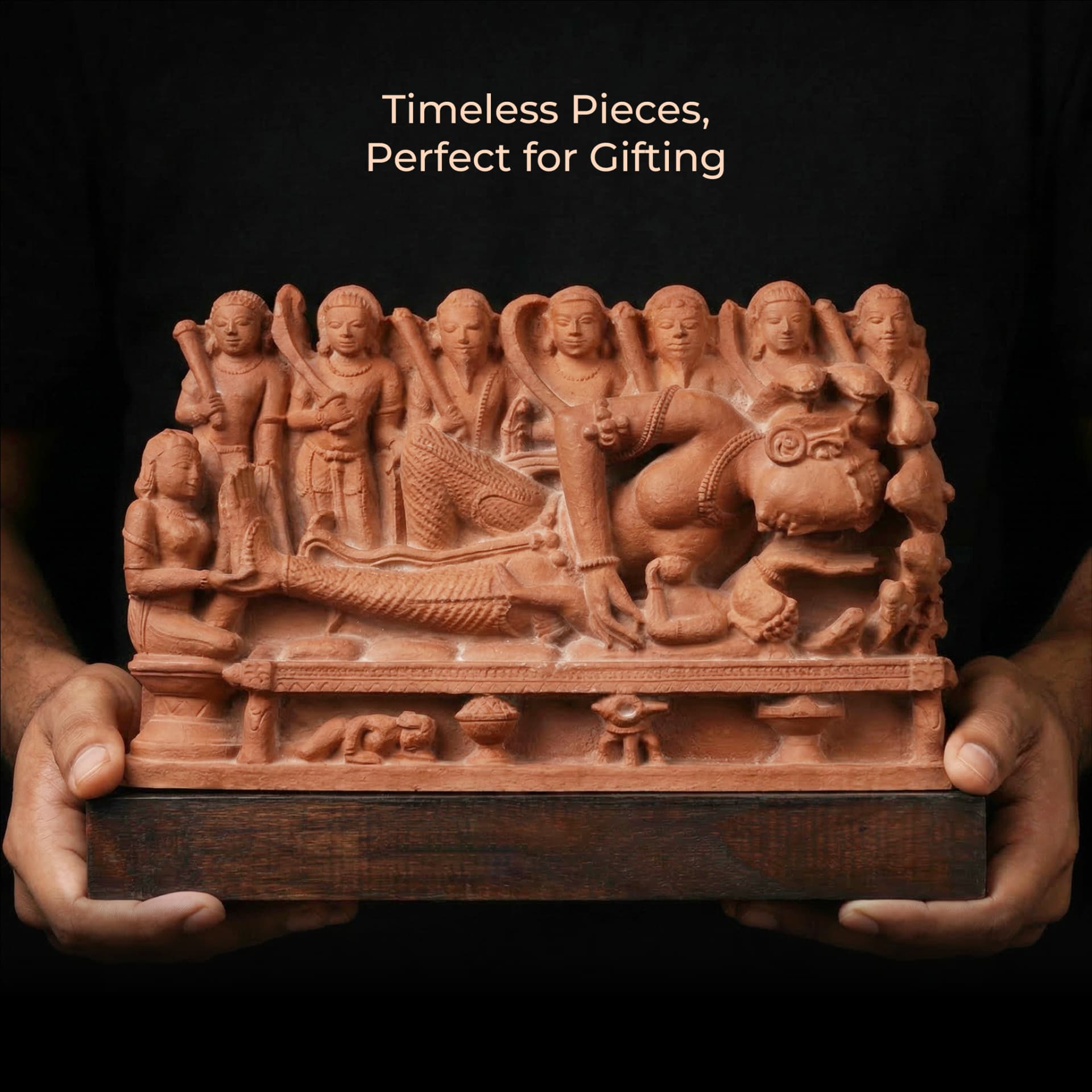 A person holds a terracotta-style Krishna's Birth Sculpture, showcasing intricate 10th-century temple art details against a black background.