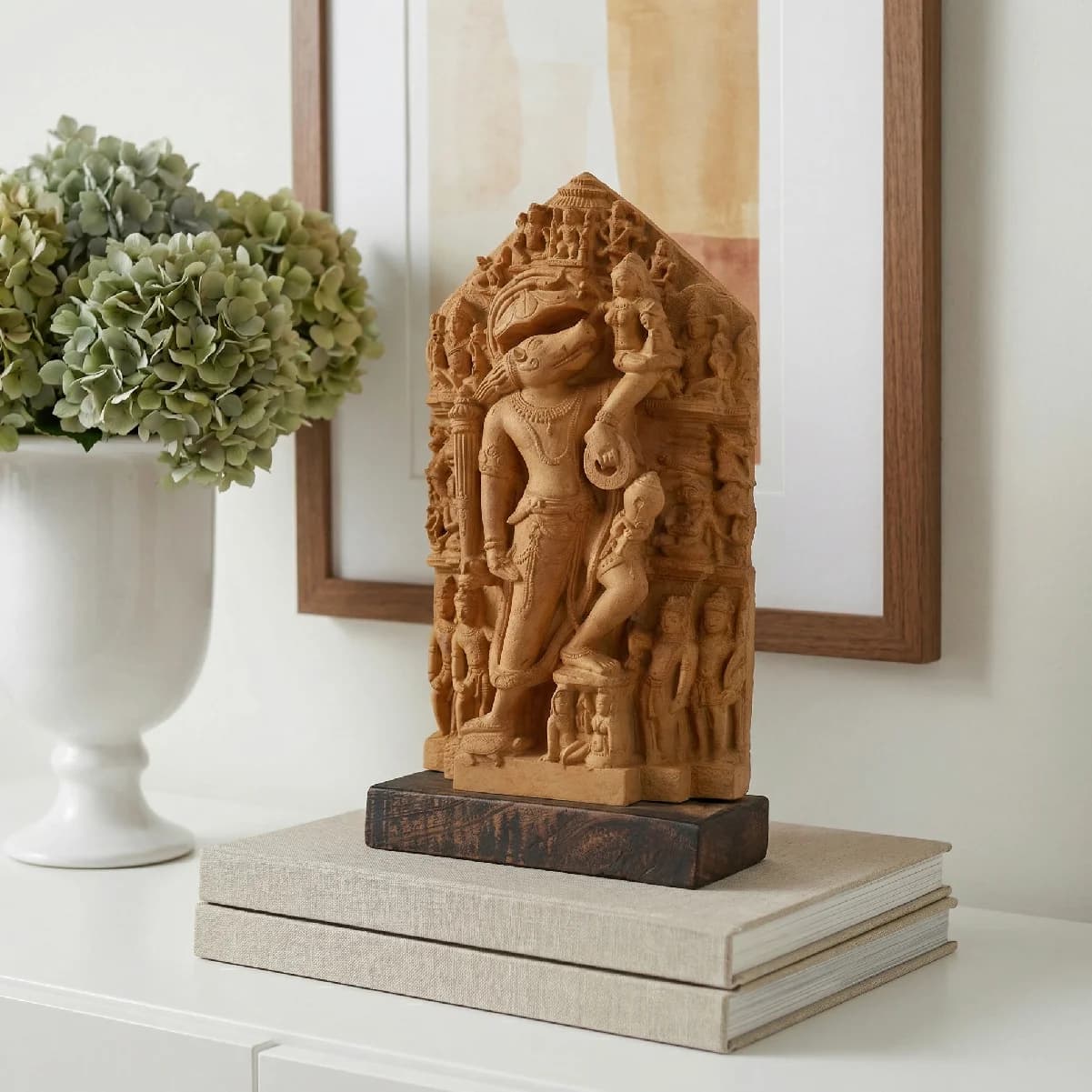 A stone composite Nar Varaha Sculpture replica displayed on books, featuring intricate temple art details of the man-boar Vishnu avatar.