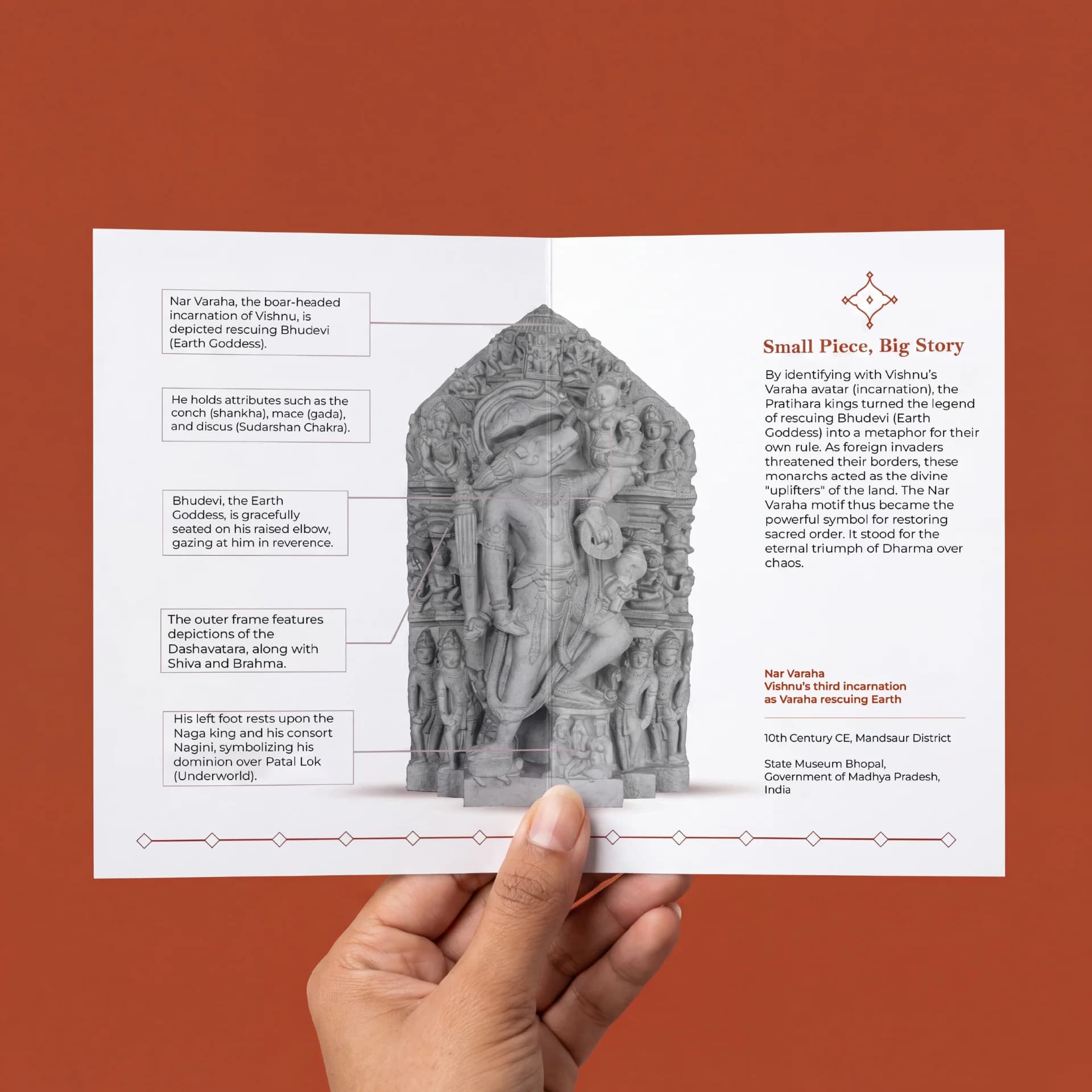 A hand holds an informational brochure featuring the Nar Varaha Sculpture, showcasing detailed stone composite craftsmanship and historical context.