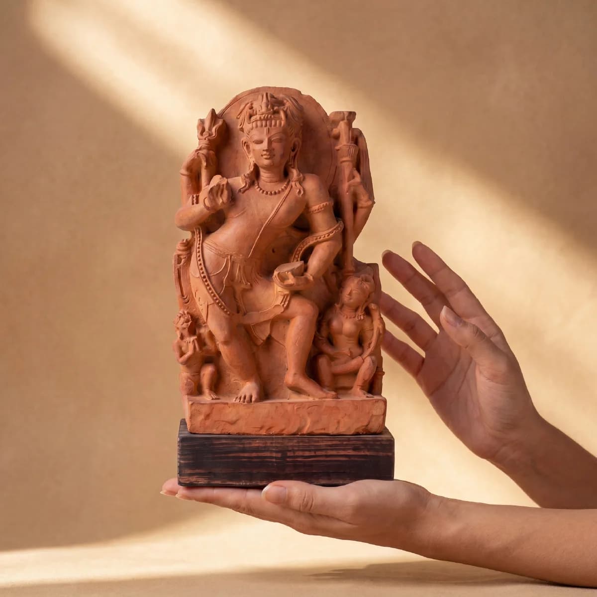 A pair of hands gently holds the Natesh Shiva Sculpture, a hand-finished stone composite replica featuring intricate dancing deity details.