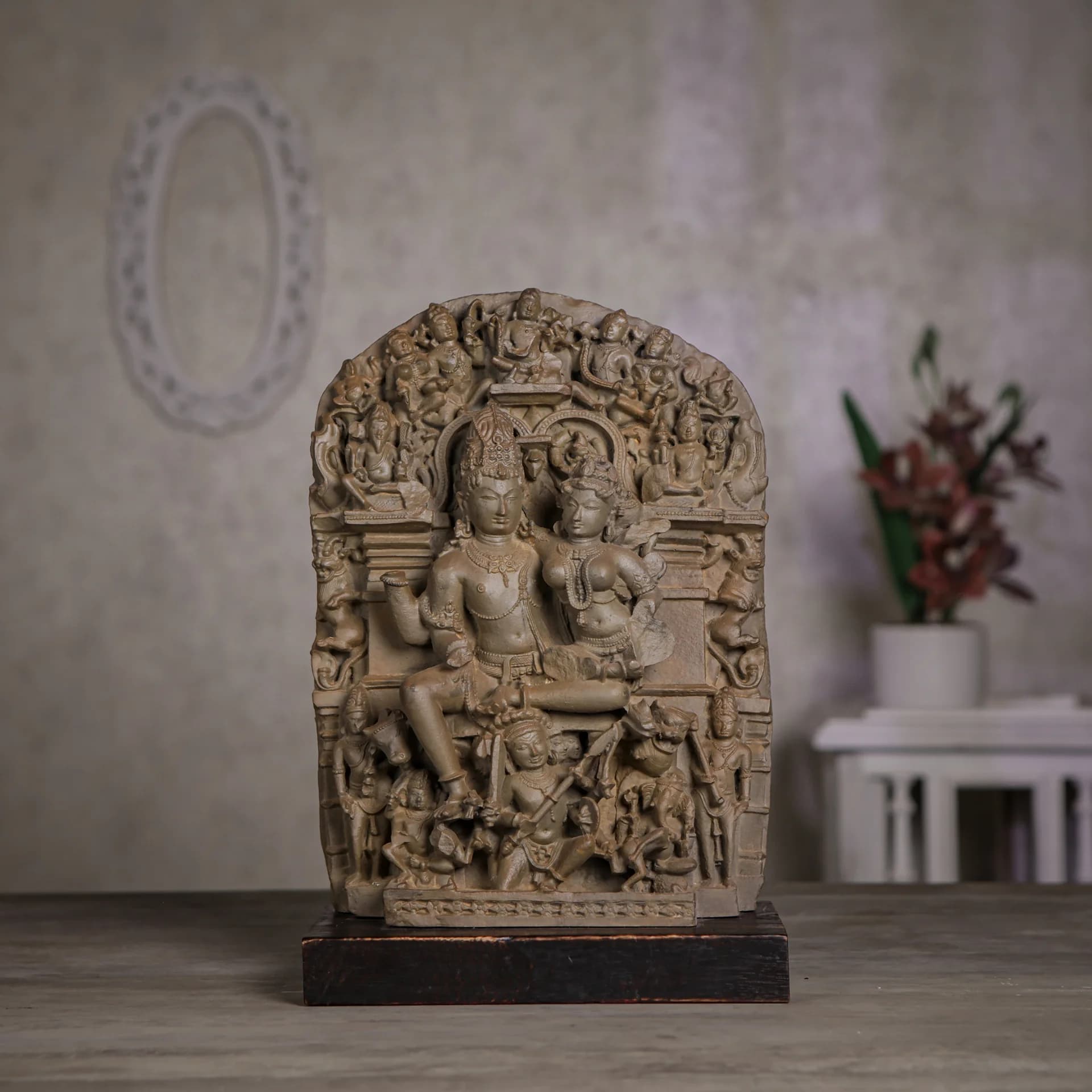 A front view of the stone composite Ravananugraha Sculpture, showcasing intricate 11th-century temple art details on a wooden base.