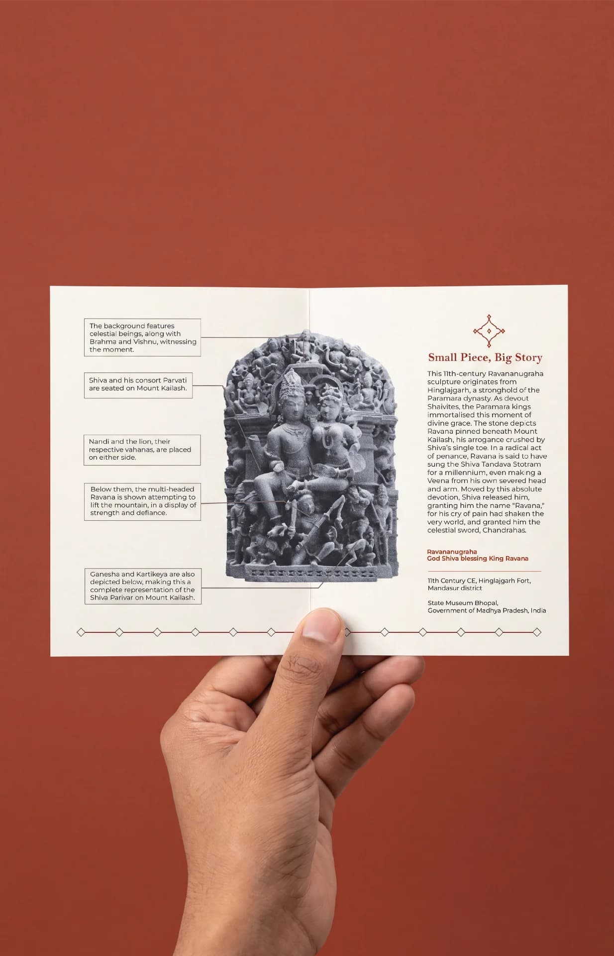 A hand holds an open brochure featuring a detailed stone composite Ravananugraha Sculpture replica with informative callout labels.