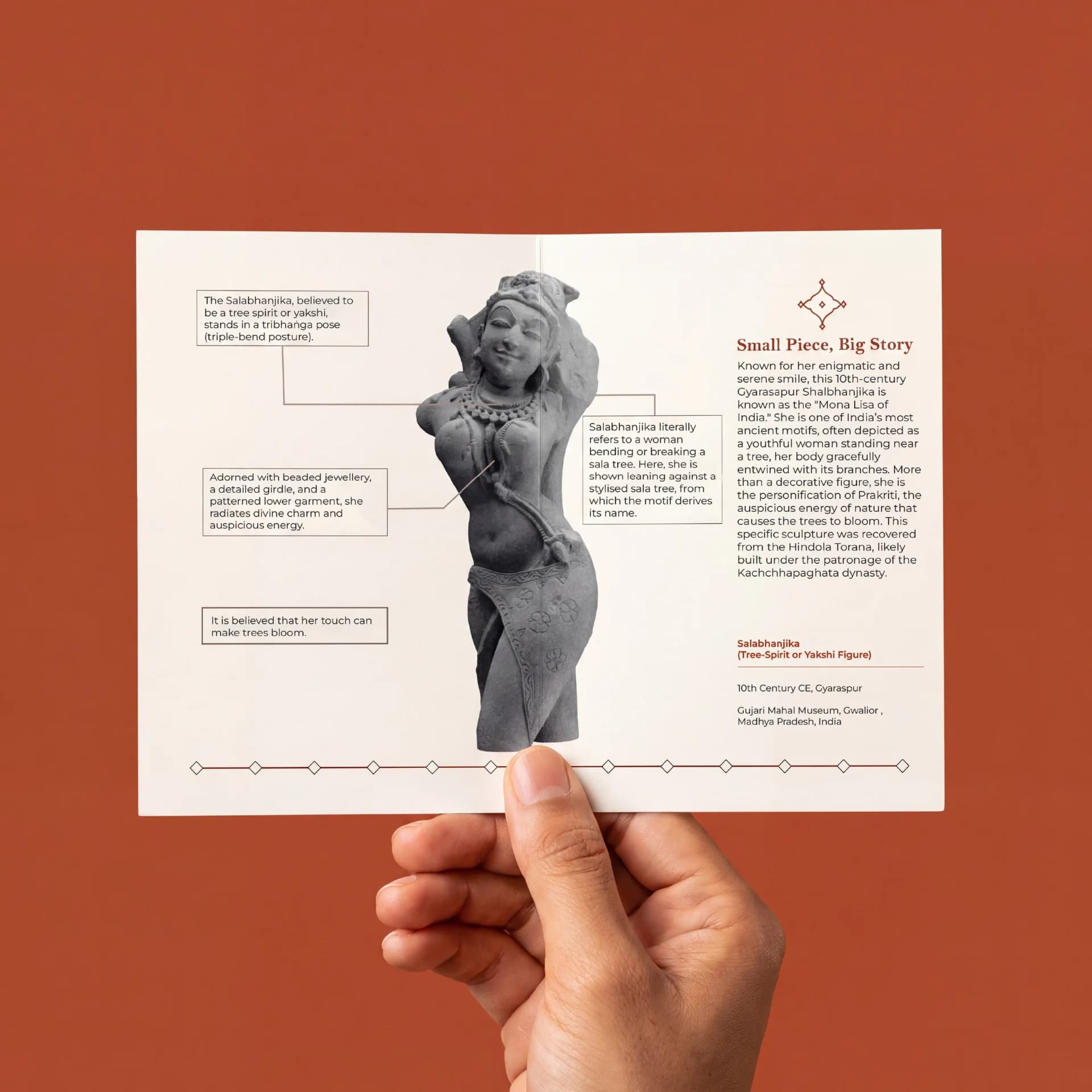 A hand holds a brochure featuring the Salabhanjika Sculpture, displaying detailed historical annotations about this stone composite museum replica.
