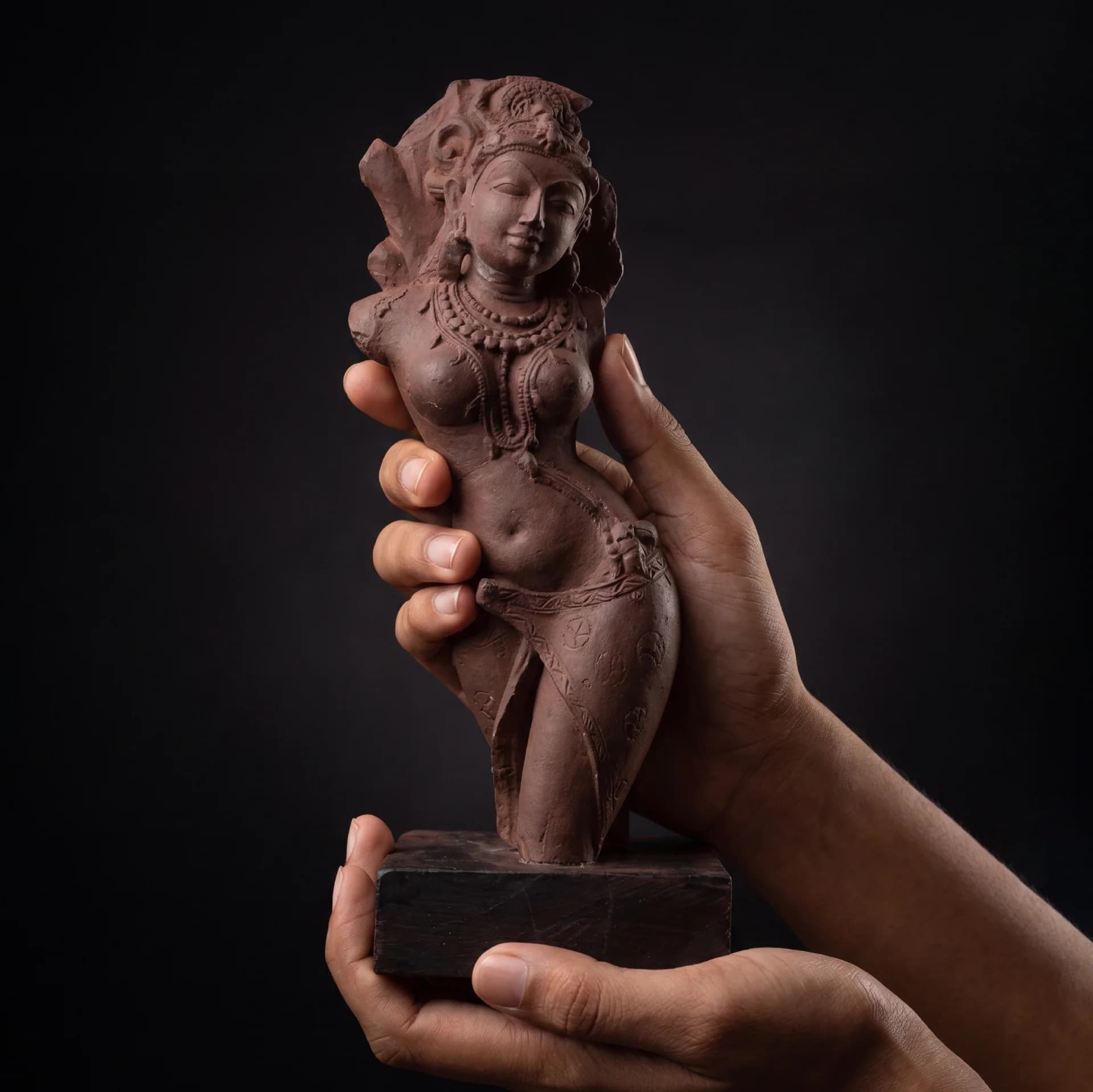 Hands holding a stone composite Salabhanjika Sculpture, showcasing the intricate details of this 10th-century Indian temple bracket figure replica.