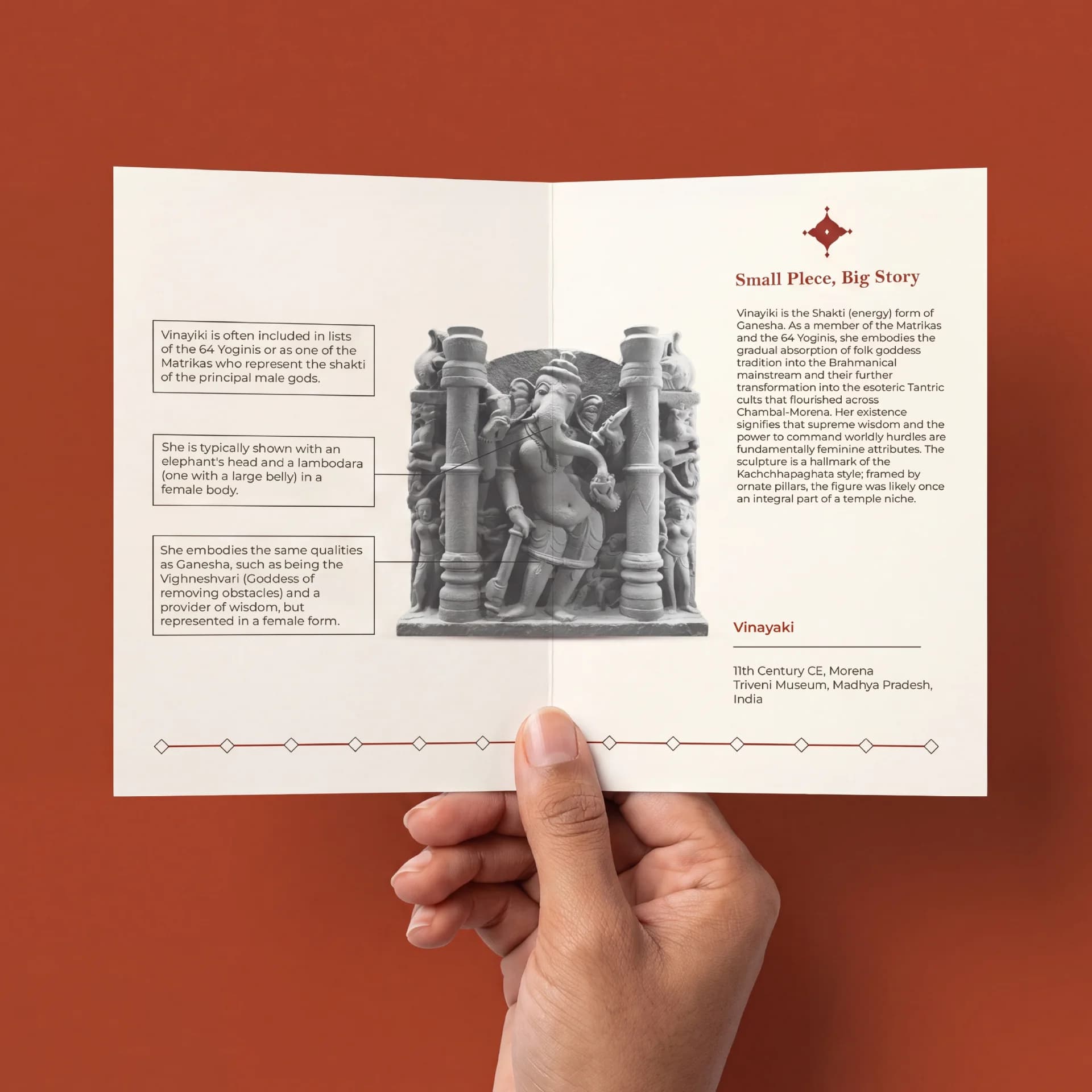 A hand holds an open brochure featuring the Vinayaki Sculpture, a detailed stone-style replica with educational text and diagrams.