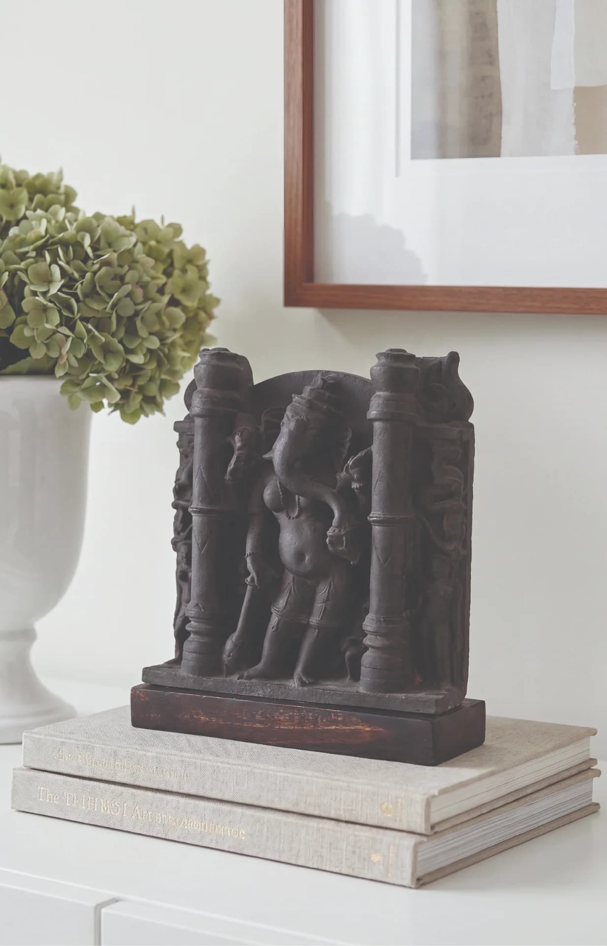 The Vinayaki Sculpture displayed on stacked books, showcasing the dark stone-finish texture of this rare Hindu temple art replica.