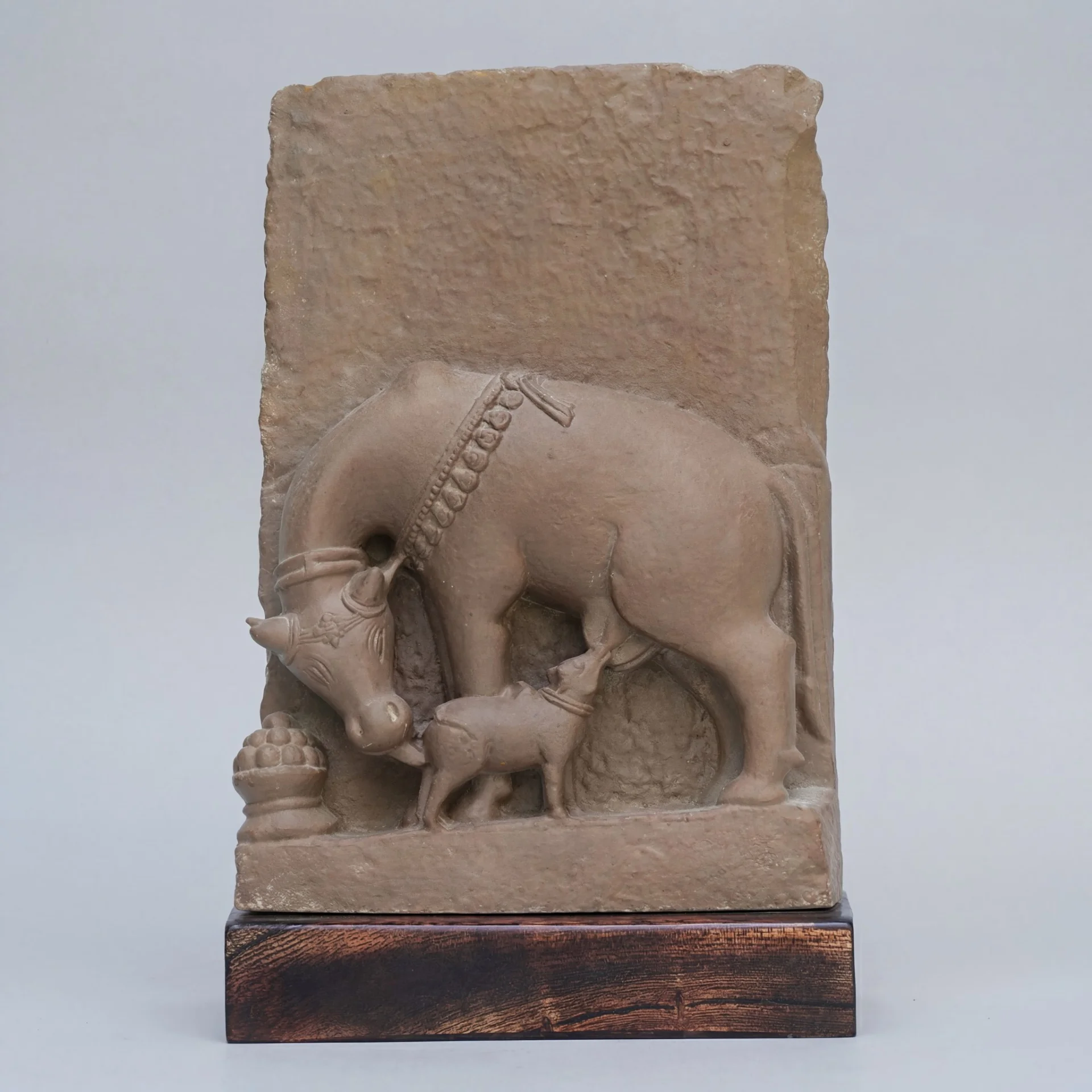 A front view of the Kamdhenu Sculpture, a stone composite relief depicting a cow nursing its calf with traditional ornamentation.