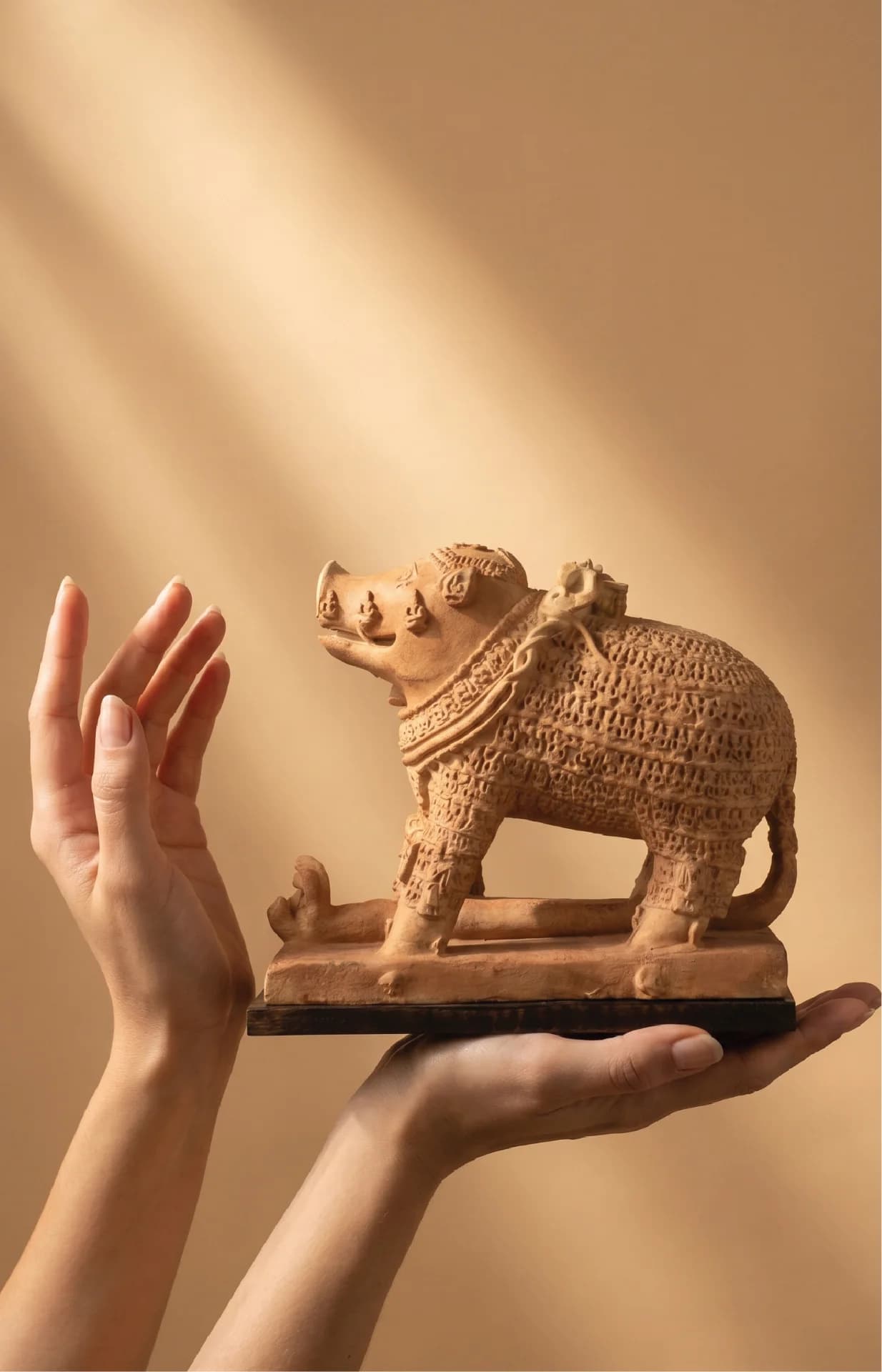 A person holds a terracotta Adi Varaha Sculpture, showcasing the intricate carved details of the ancient Hindu deity replica.