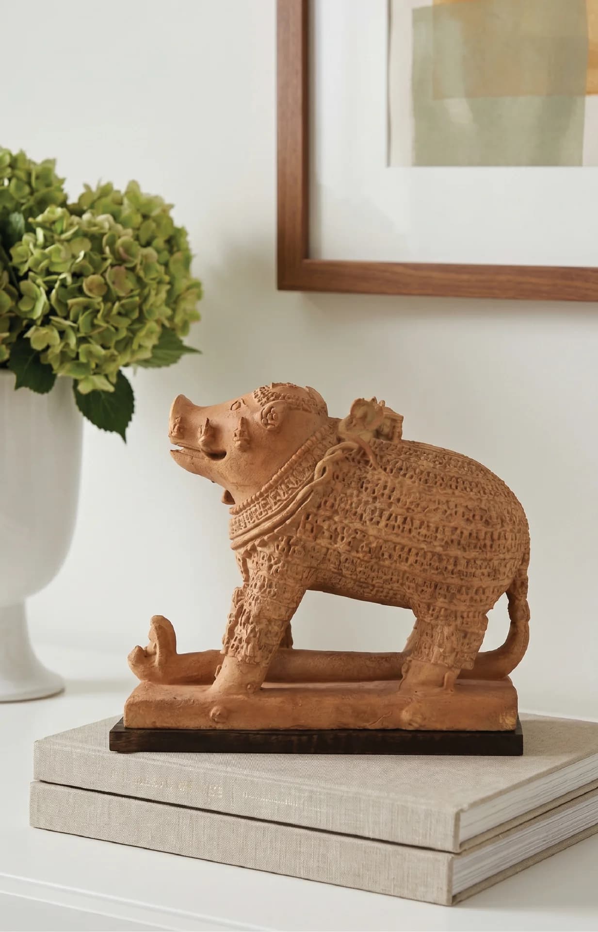 The Adi Varaha Sculpture, a detailed terracotta-style museum replica, sits on a stack of books as elegant home decor.