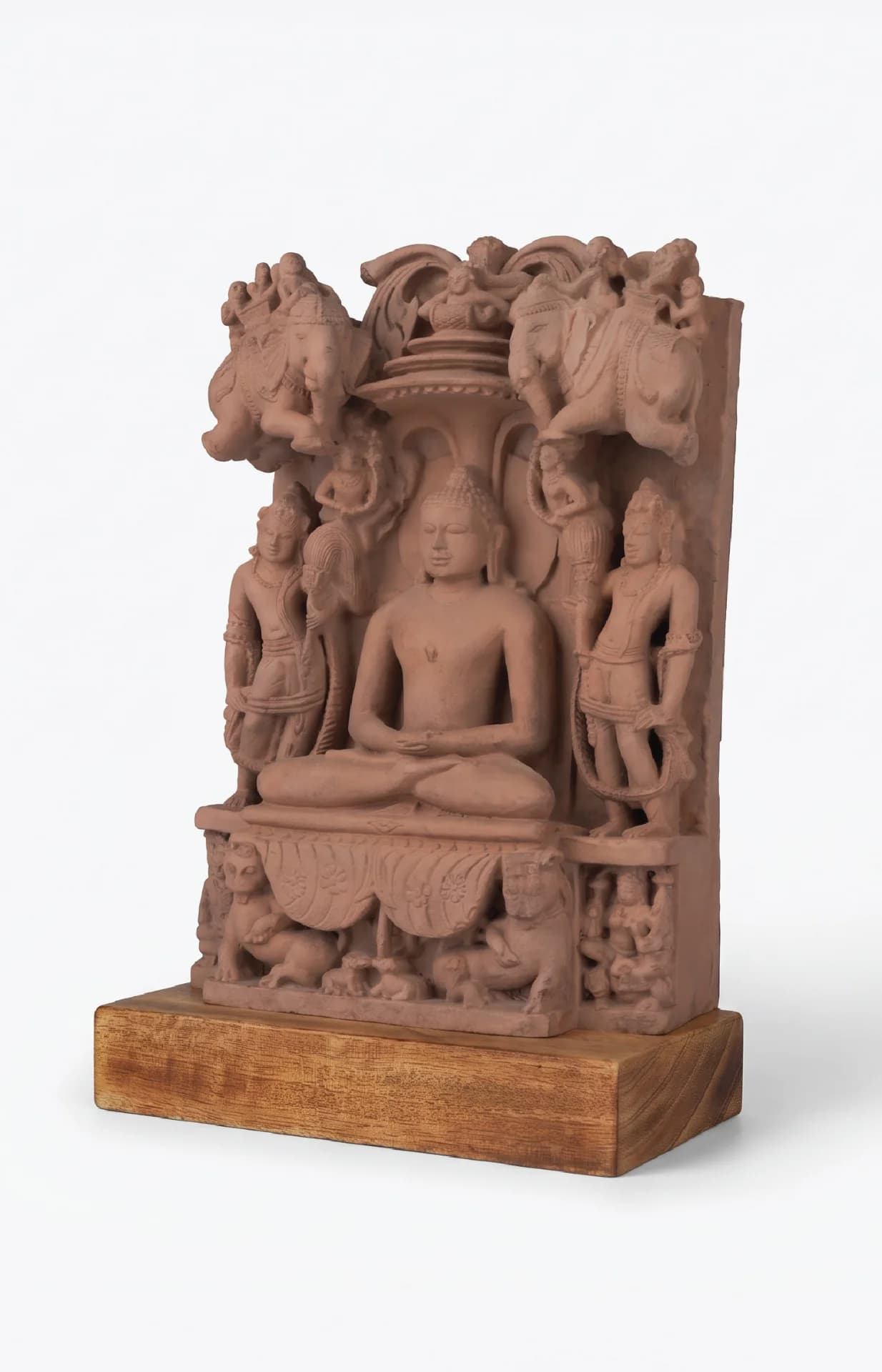 A stone composite Adinath Sculpture museum replica showing the Tirthankara seated in meditation, flanked by intricate attendant figures.