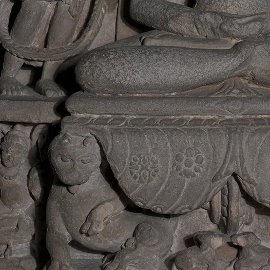 Close-up of the stone composite Adinath Sculpture base, showing intricate carvings of a lion and floral motifs.
