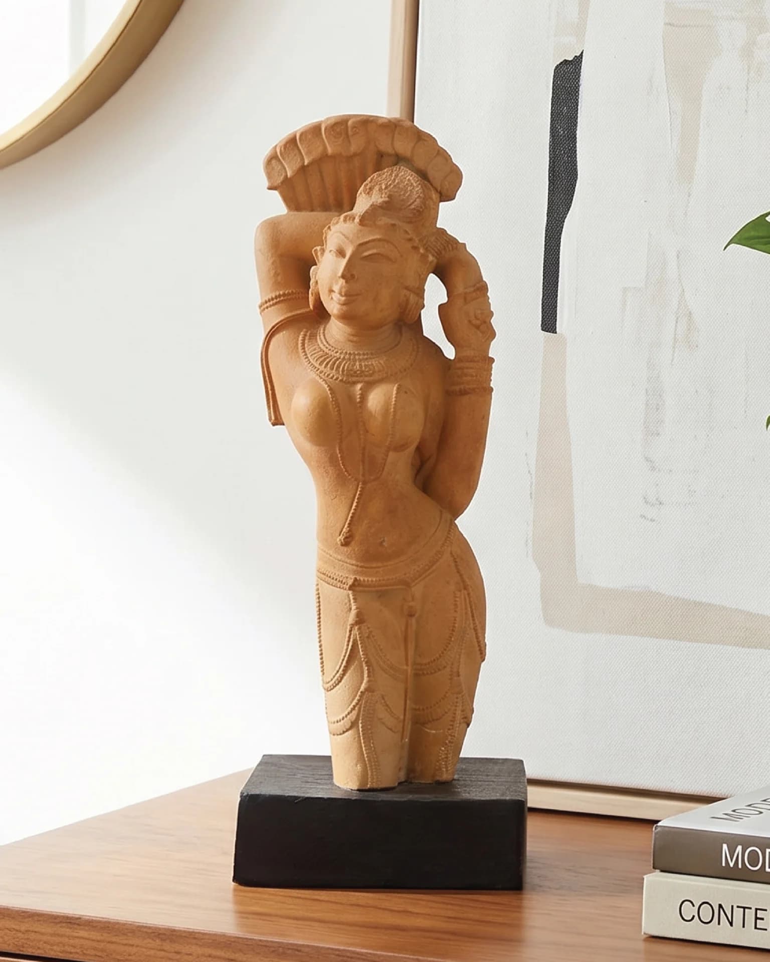 The Alasa Nayika Sculpture stands on a wooden table, featuring hand-finished stone composite details in a classic tribhanga pose.