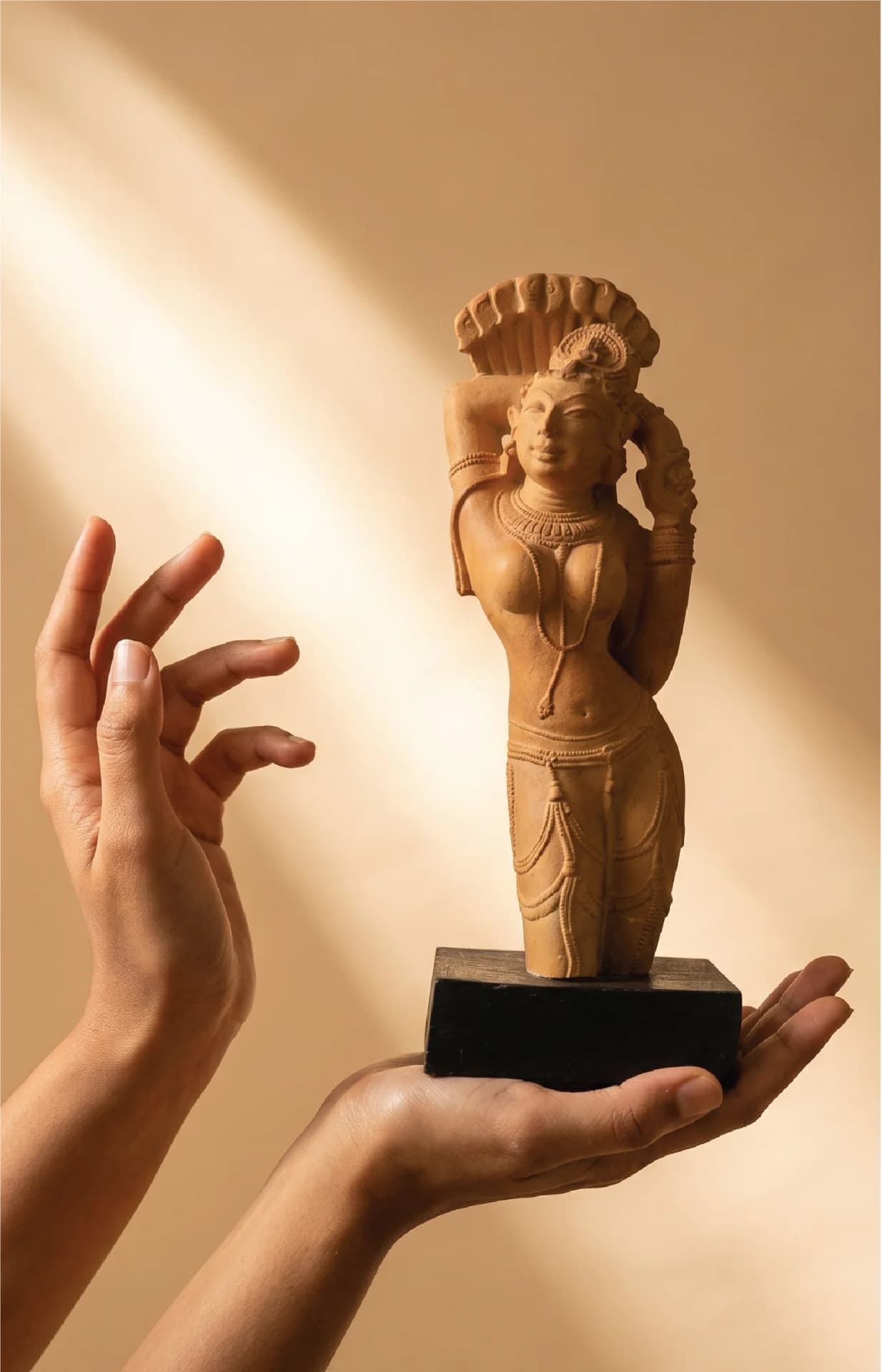 A pair of hands gently cradles the Alasa Nayika sculpture, a stone composite replica featuring intricate celestial Indian temple art.