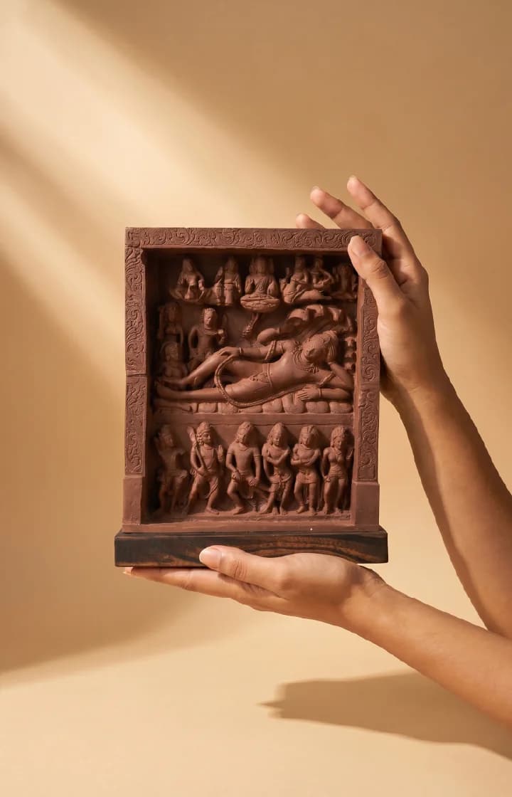 Hands hold an Anantasayana Vishnu Sculpture, a terracotta-style museum replica featuring intricate Gupta-period relief carvings of reclining deities.