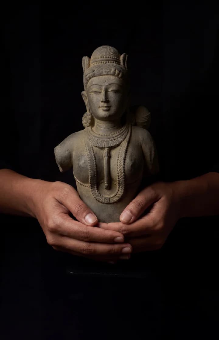 Close-up of hands cradling a Female Figure Bust Sculpture, showcasing the smooth stone composite texture and elegant Chola-style craftsmanship.