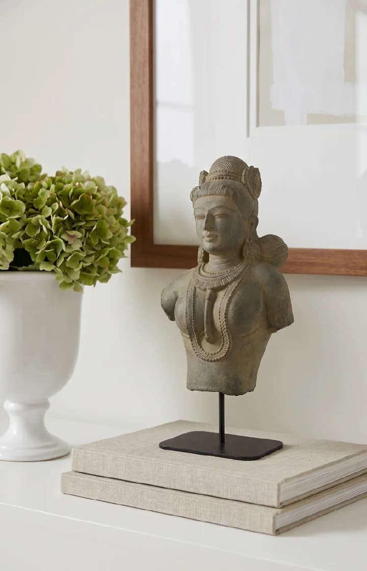 A Female Figure Bust Sculpture displayed on a pedestal, showcasing the smooth stone composite texture and elegant Chola-inspired details.