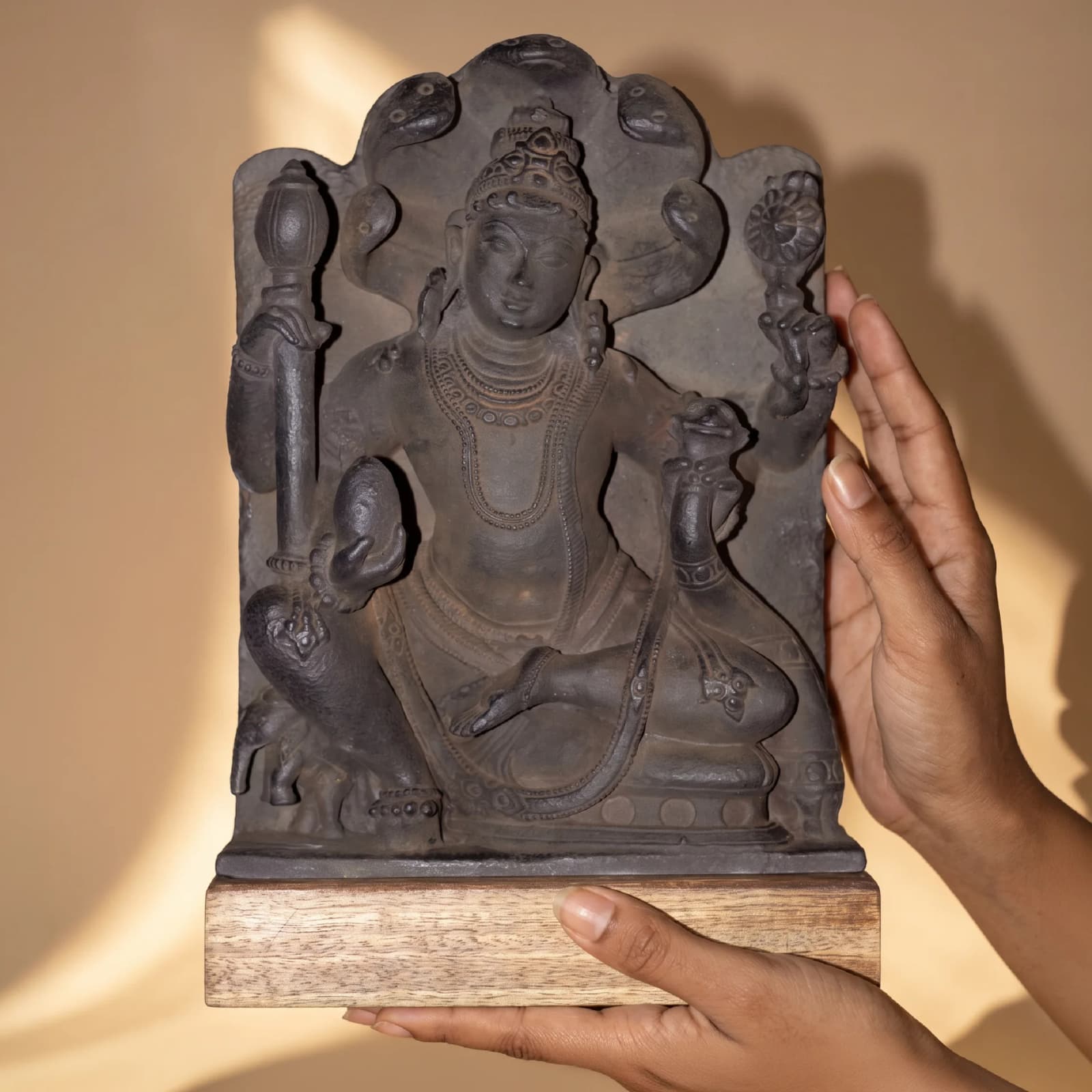 Hands hold a hand-finished stone composite Dhan Kuber Statue for Home & Vastu, showcasing intricate 11th-century sculptural details.