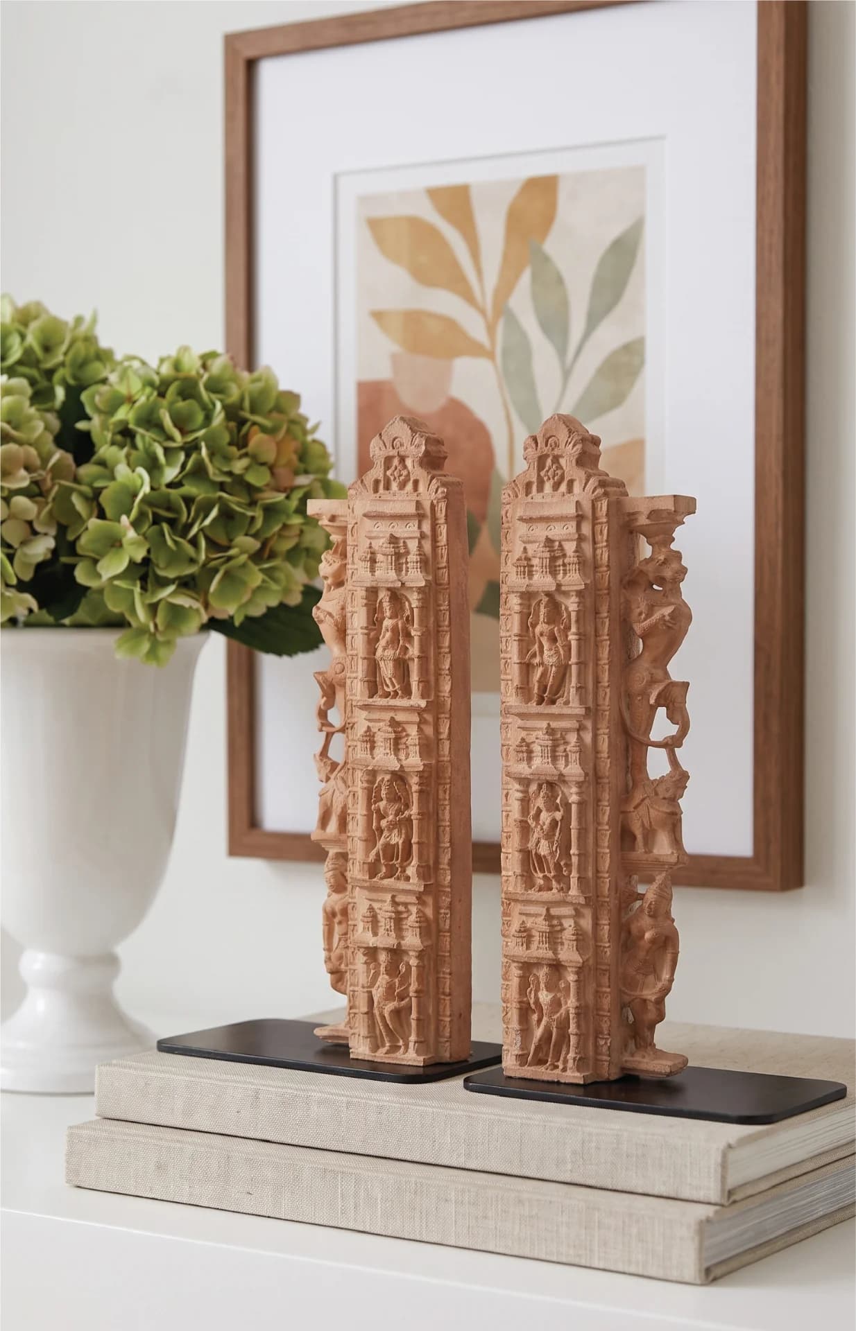 A pair of Dwara Shakha Sculpture bookends crafted from stone composite, displayed on stacked books with a vase.