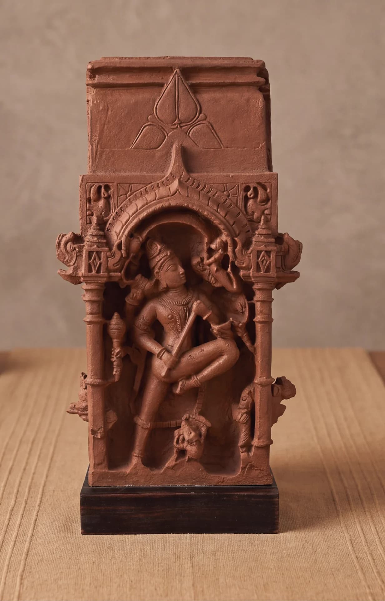 A front-facing view of the Gajasura Vadha Sculpture, a terracotta-style museum replica depicting Shiva in a dynamic temple relief.