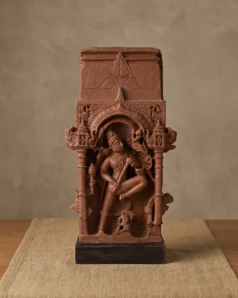 A front view of the Gajasura Vadha sculpture, a terracotta-style museum replica showing Shiva in a dynamic temple relief.