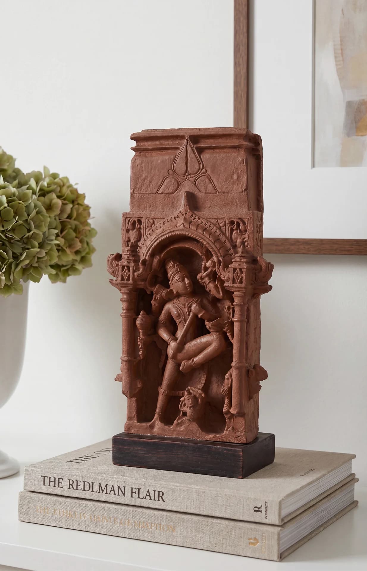 A terracotta-style Gajasura Vadha Sculpture displayed on stacked books, showcasing intricate temple relief carvings of Shiva in a museum-replica finish.