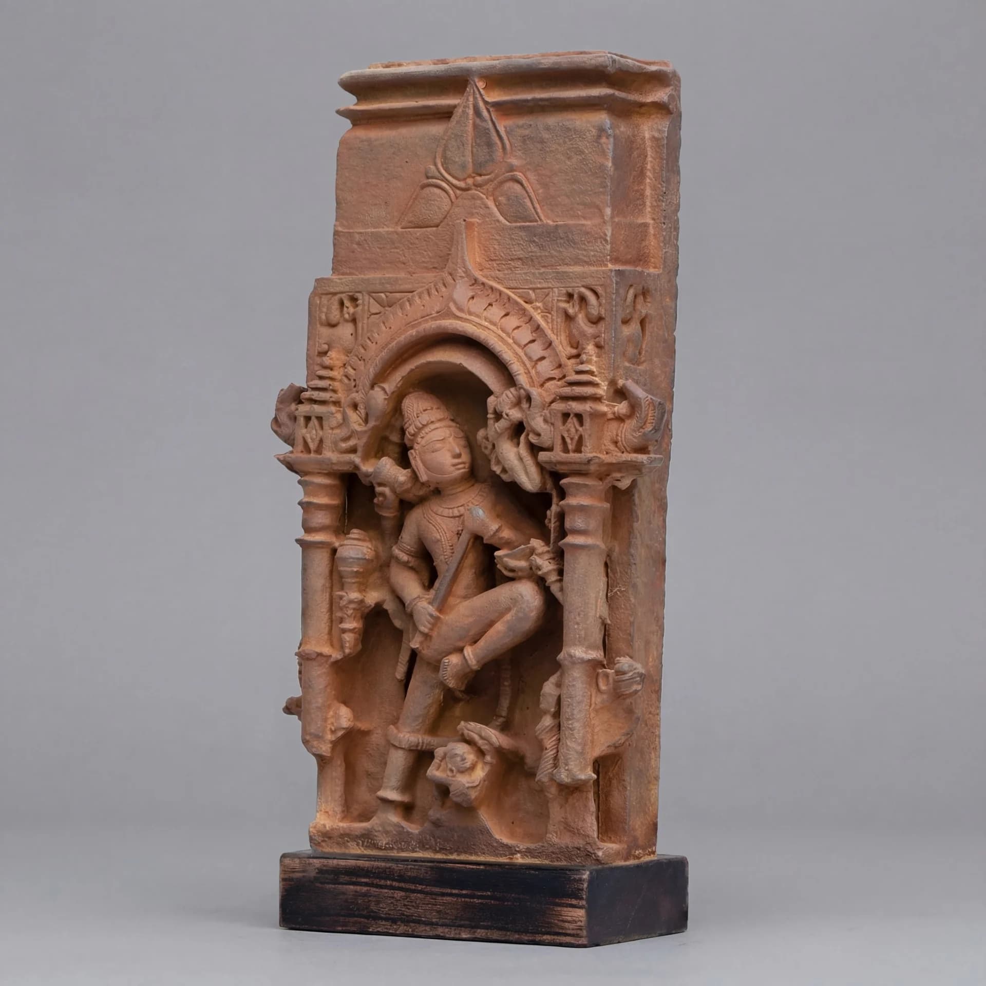 A three-quarter view of the Gajasura Vadha Sculpture, a stone composite replica featuring intricate temple relief carvings of Shiva.
