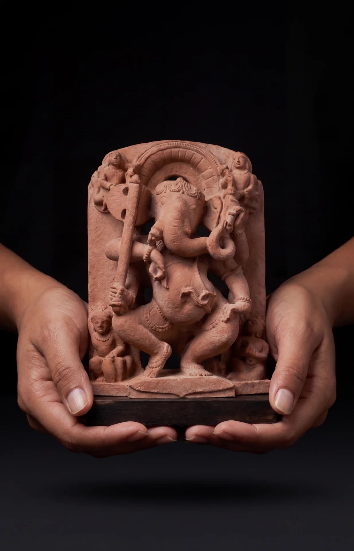 A pair of hands holds the Ganesha & Lakshmi Narayan Museum Masterpiece Replicas, showcasing the intricate terracotta-style dancing Ganesha.