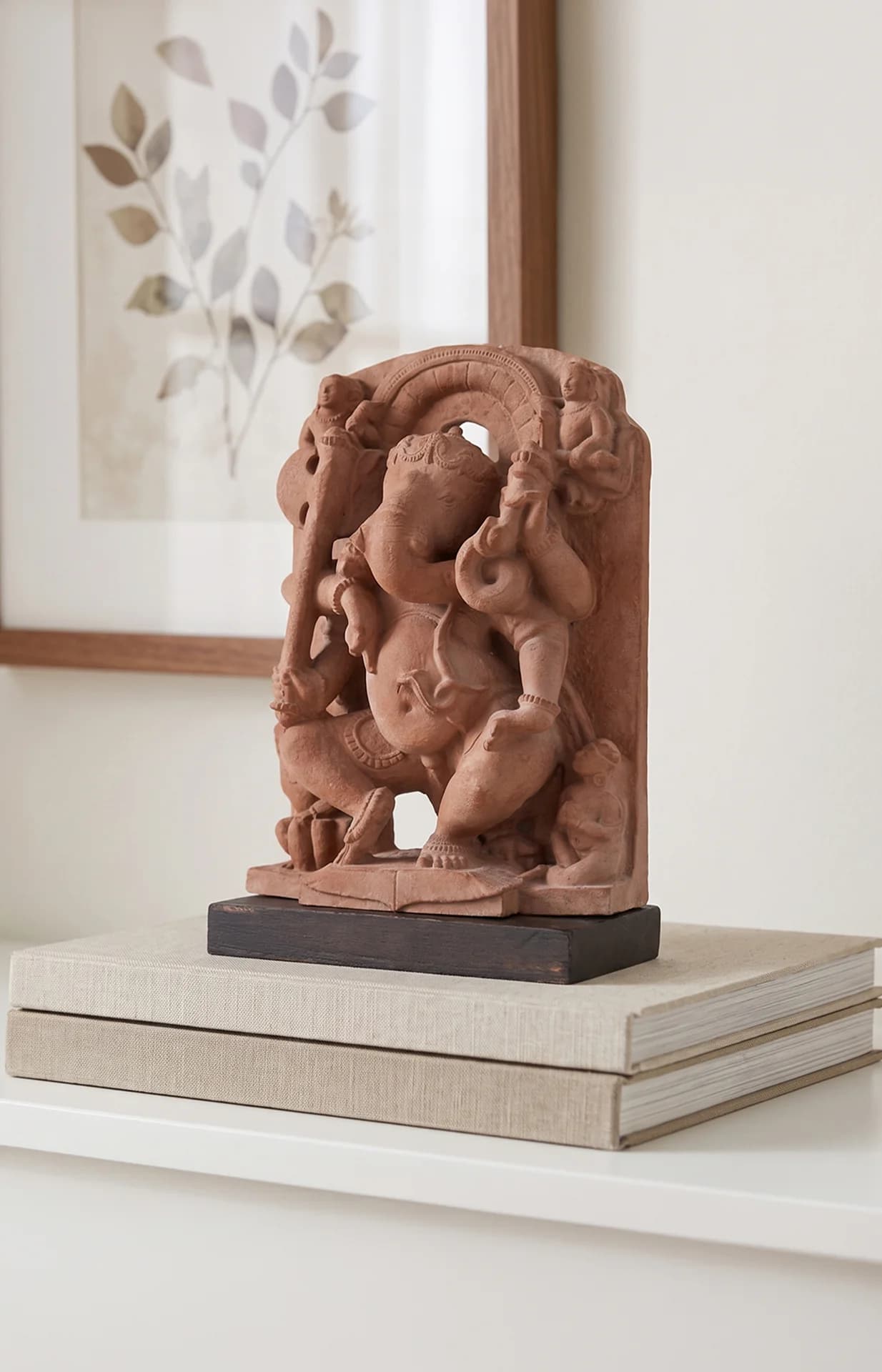 A stone composite Ganesha Sculpture displayed on books, showcasing the intricate 10th-century temple art replica in a home setting.