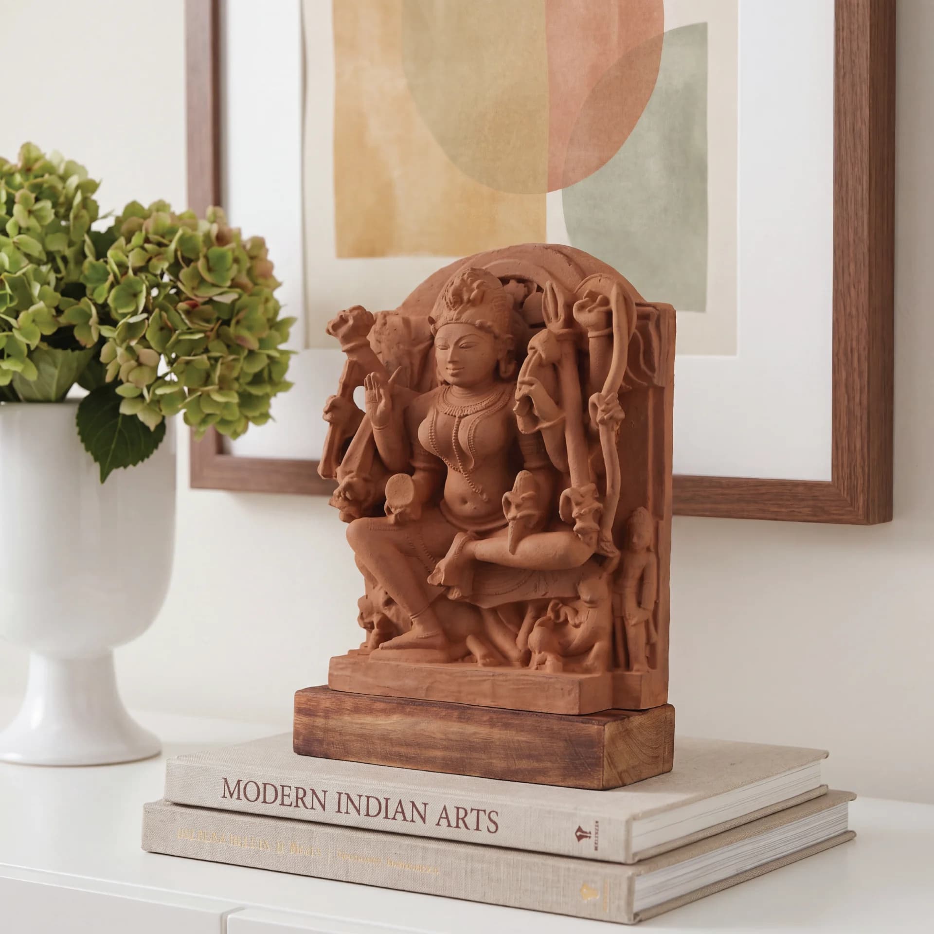 The Goddess Durga Sculpture sits on a stack of books, showcasing the intricate hand-finished stone craftsmanship of this museum-replica piece.