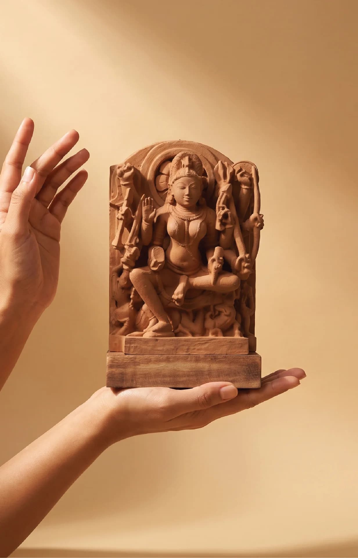 A pair of hands gently cradles the stone Goddess Durga Sculpture, showcasing the intricate hand-finished details of the medieval-inspired figure.
