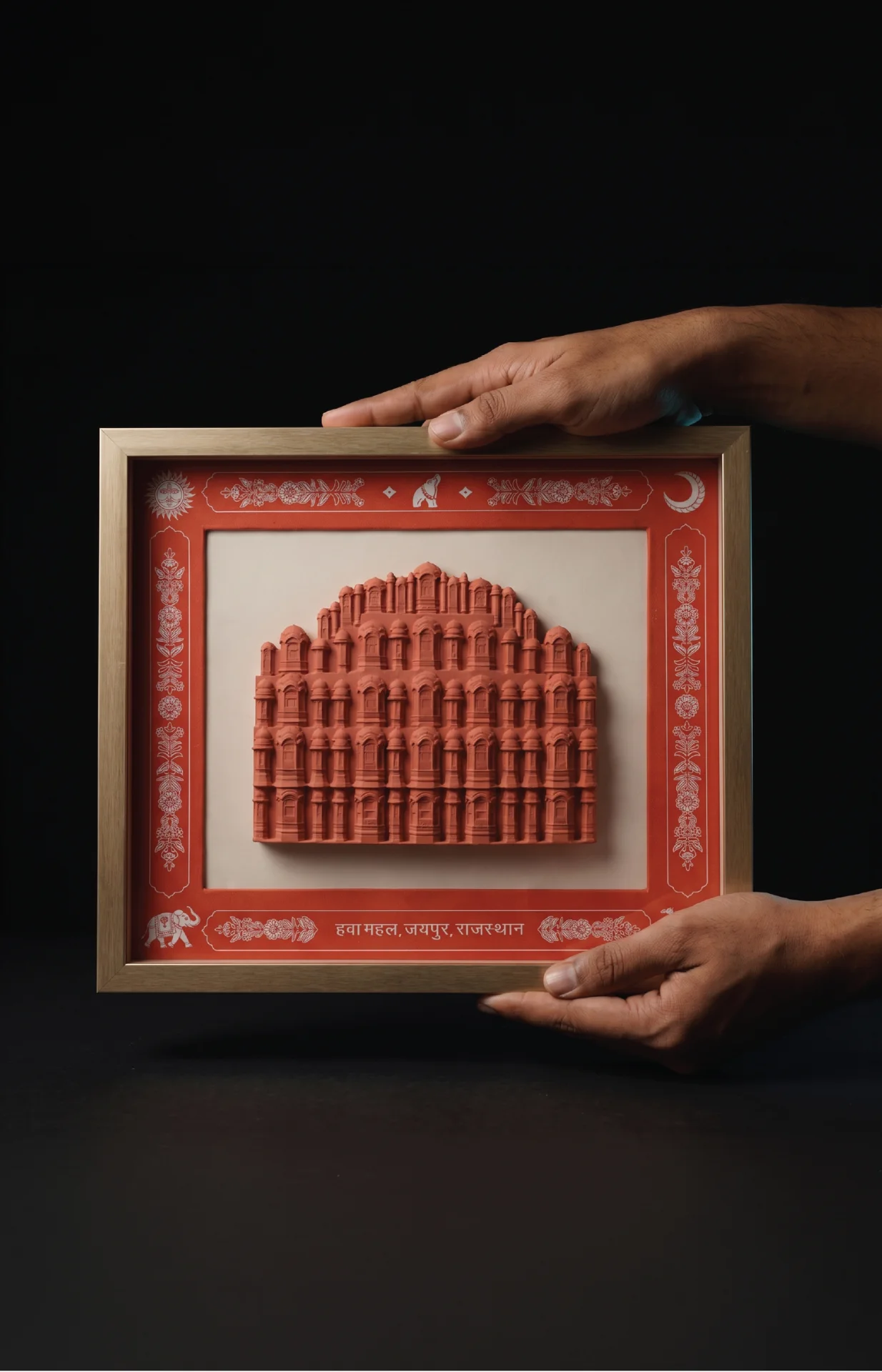 A pair of hands holds a framed Hawa Mahal Facade Sculpture featuring a detailed terracotta-style relief of the iconic palace.