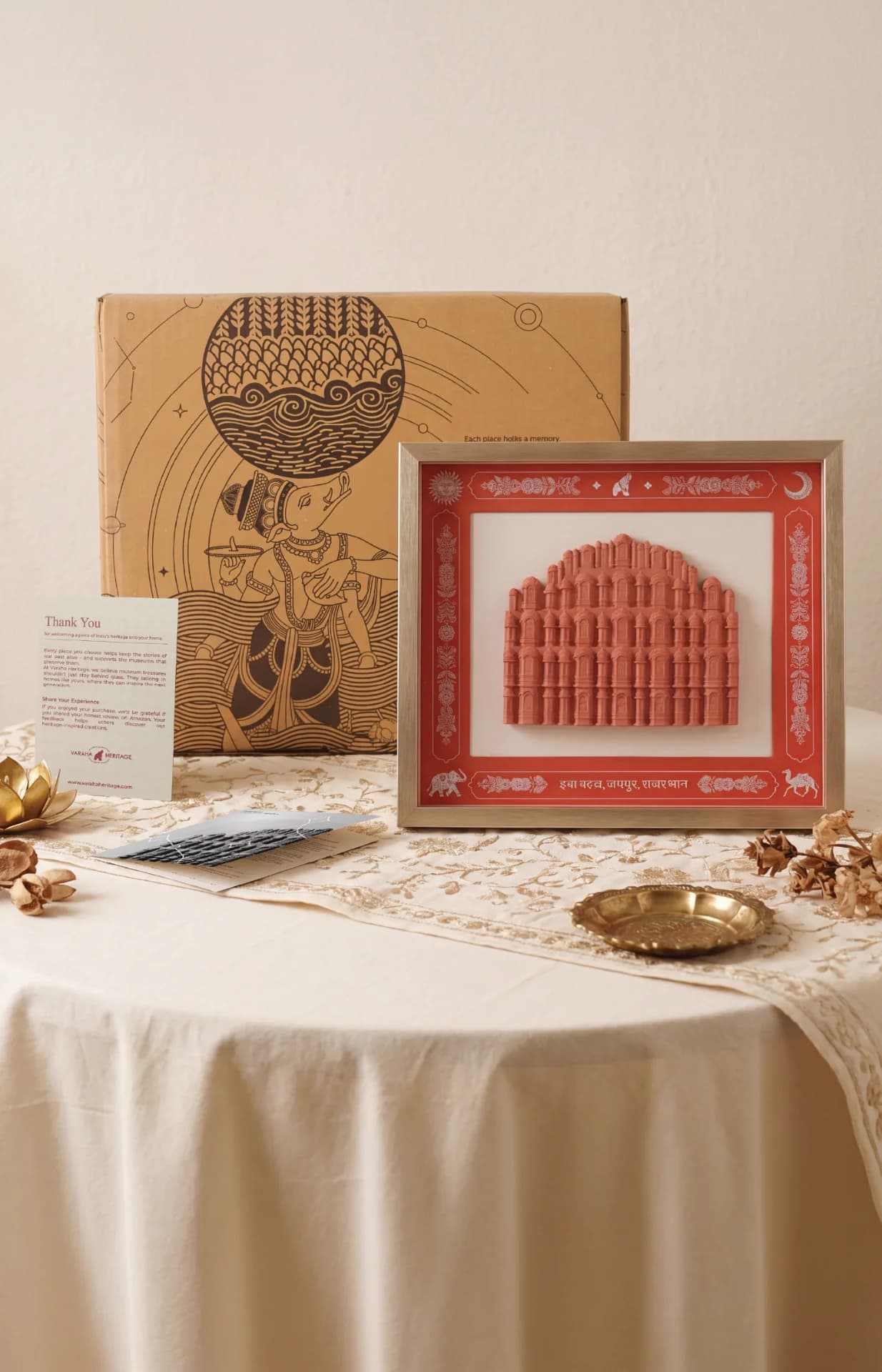 A framed Hawa Mahal Facade Sculpture in terracotta style sits on a table beside its illustrated gift box.
