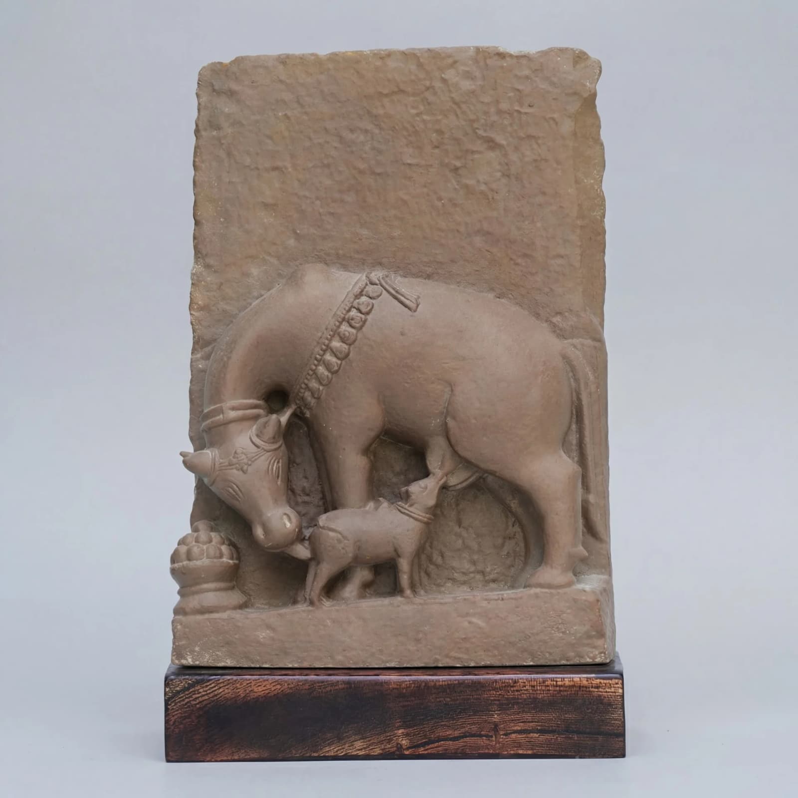 A front view of the Kamdhenu Sculpture, a stone composite relief depicting a cow nursing its calf with traditional ornamentation.