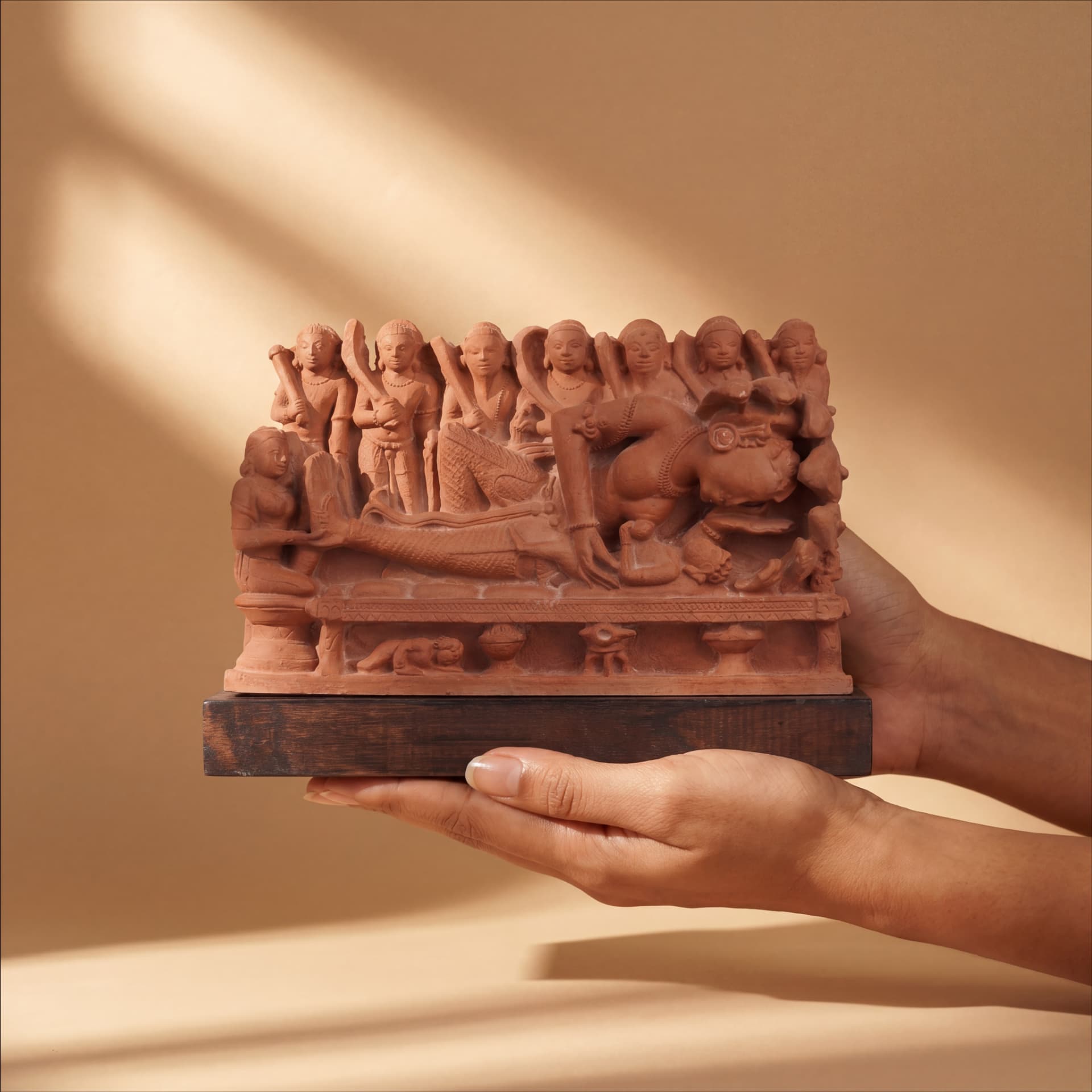 Hands holding a detailed terracotta Krishna's Birth Sculpture, a museum-grade replica featuring intricate figures of Devaki and prison guards.