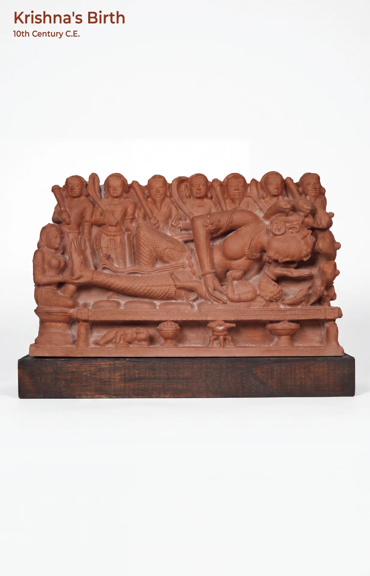 A terracotta-style Krishna's Birth Sculpture showing Devaki cradling her newborn, set against a row of standing figures.