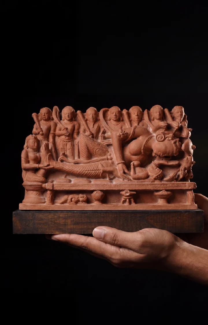 Hands hold a terracotta Krishna's Birth Sculpture, a detailed museum replica showing Devaki with her newborn and standing soldiers.